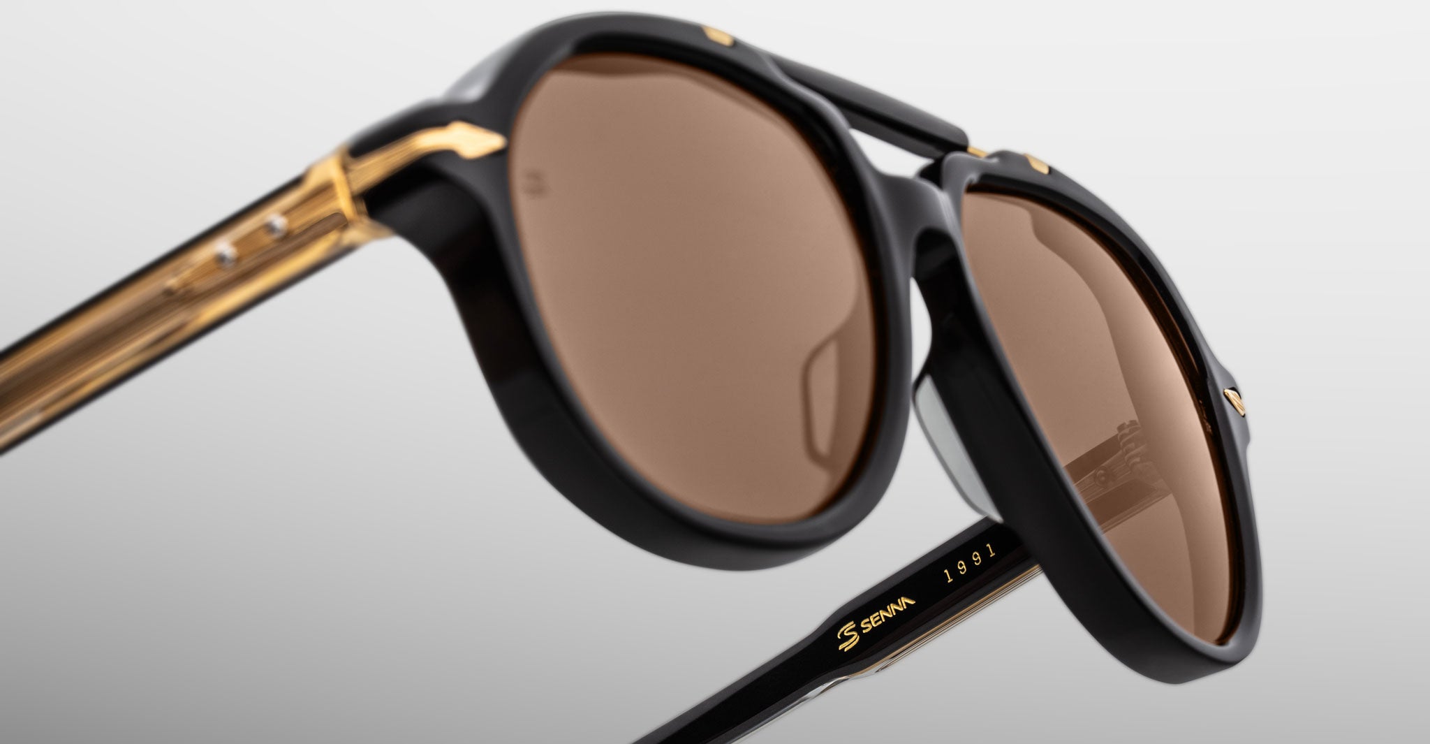 Close-up of Jacques Marie Mage 1991 sunglasses, black and gold frame with brown lenses, viewed from the front.