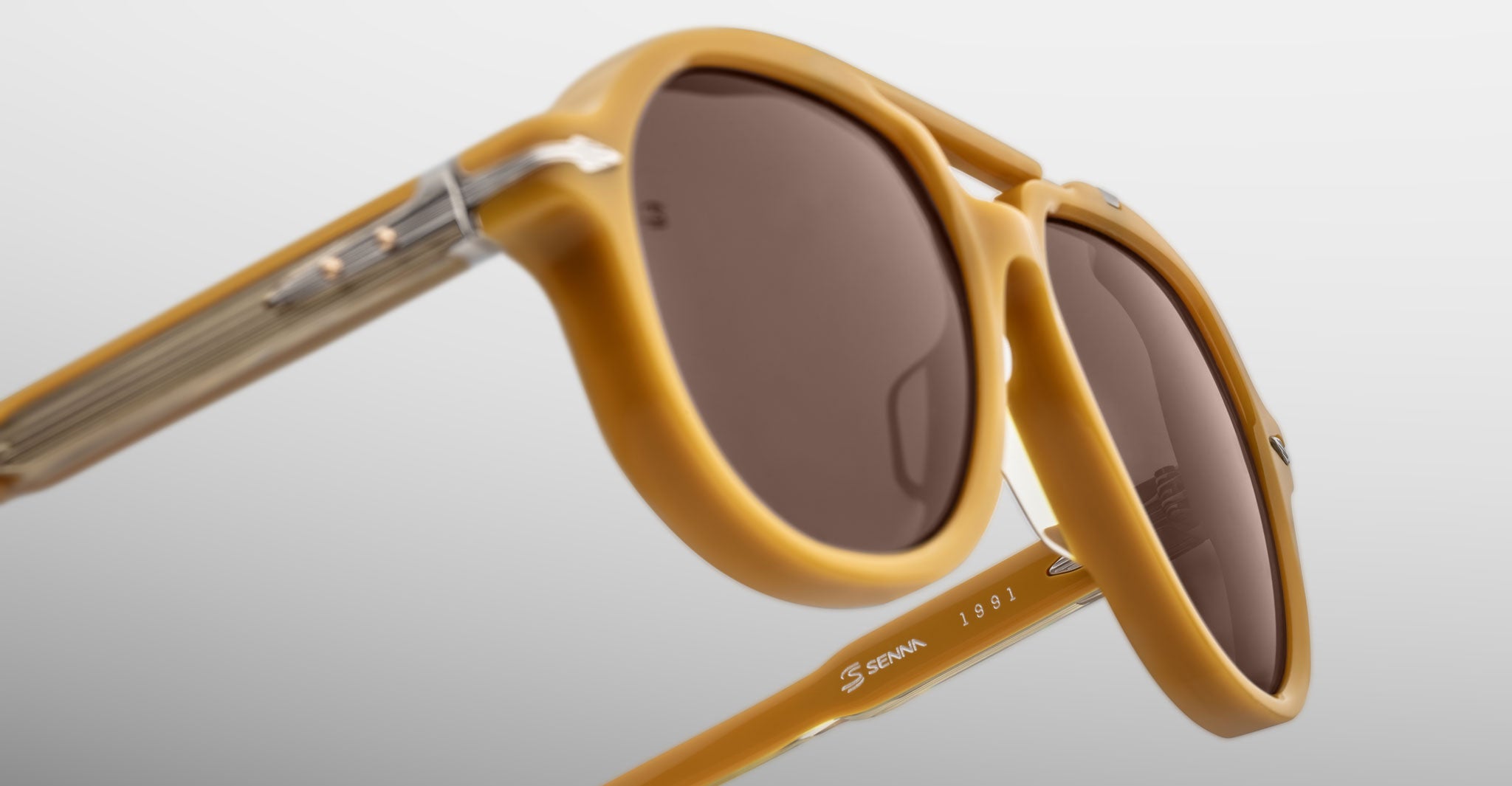 Close-up of Jacques Marie Mage 1991 sunglasses in yellow with brown lenses, detailed frame and branded temple visible from side angle.