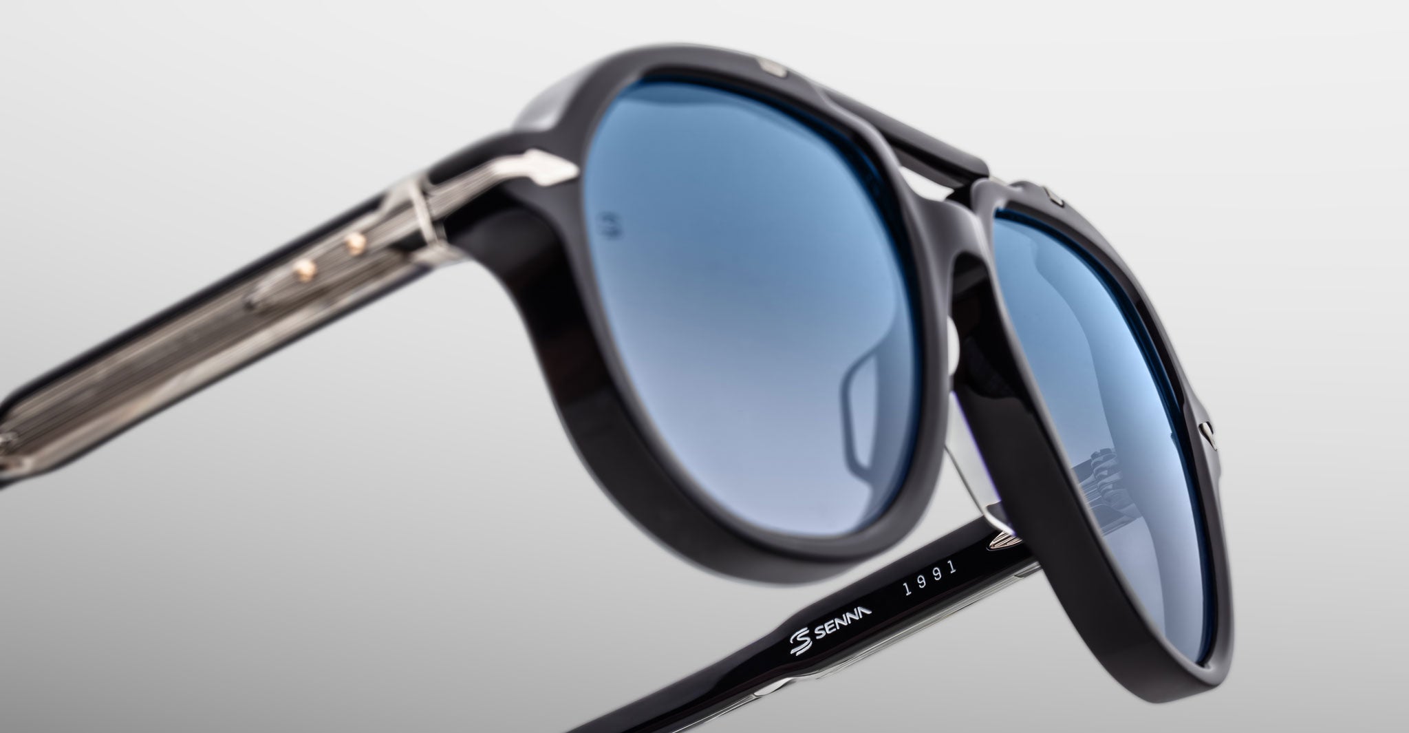 Close-up of Jacques Marie Mage 1991 sunglasses with black frames, blue lenses, and racing text on the inner arm.