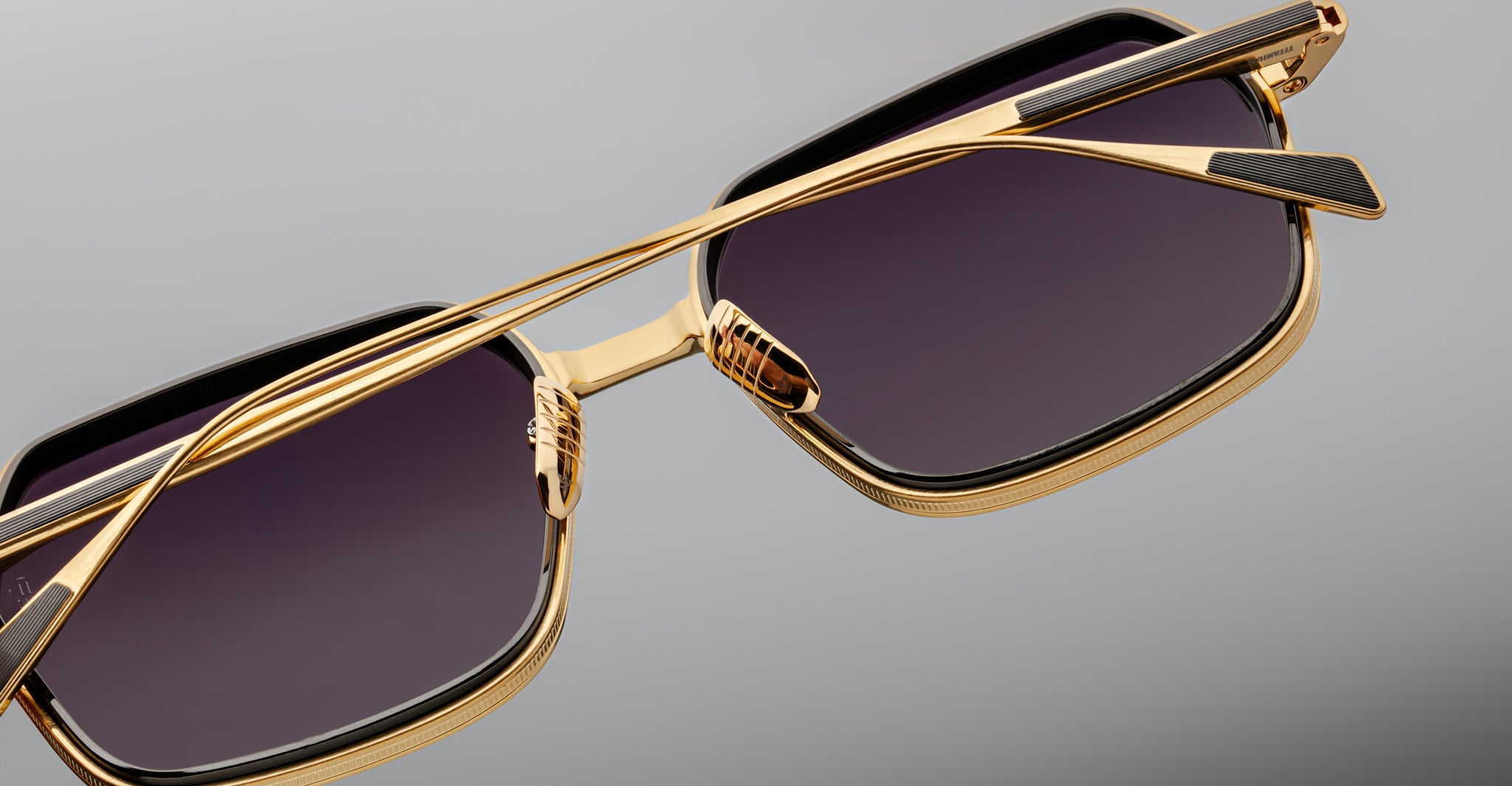Close-up of Jacques Marie Mage Admiral sunglasses with gold frames and dark rectangular lenses, front view.