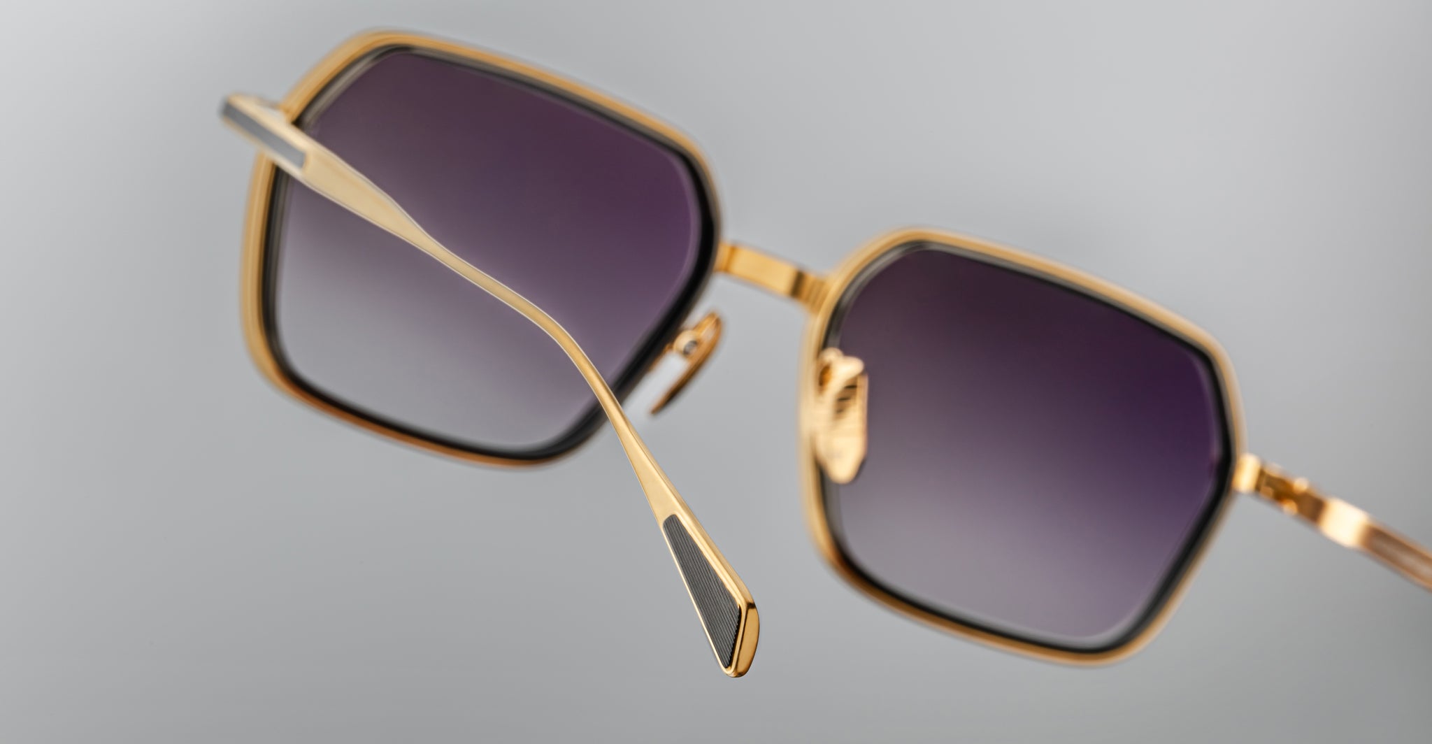 Close-up of Jacques Marie Mage Admiral square sunglasses with gold metal frames and gradient dark lenses, front angle.