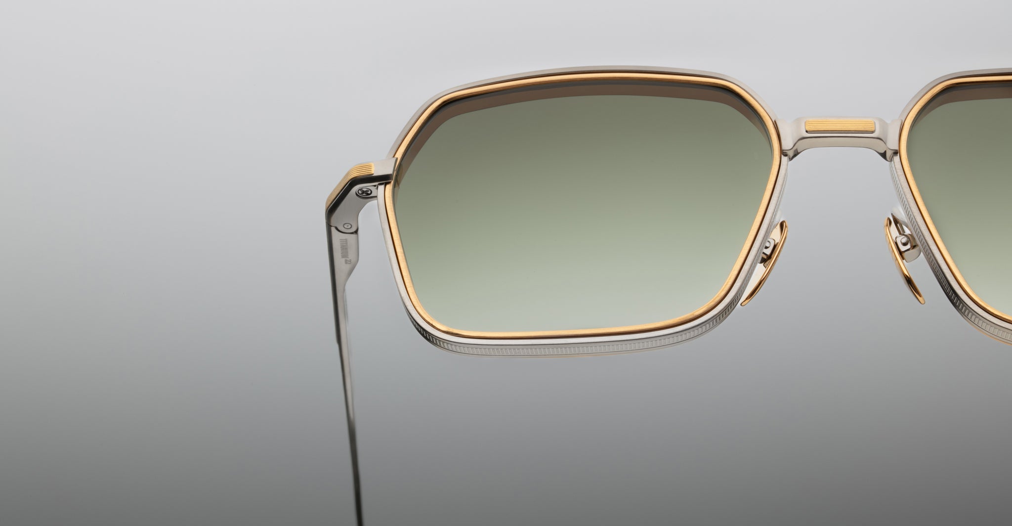 Close-up of Jacques Marie Mage Admiral sunglasses, showing gold rims and green lenses from the front angle.