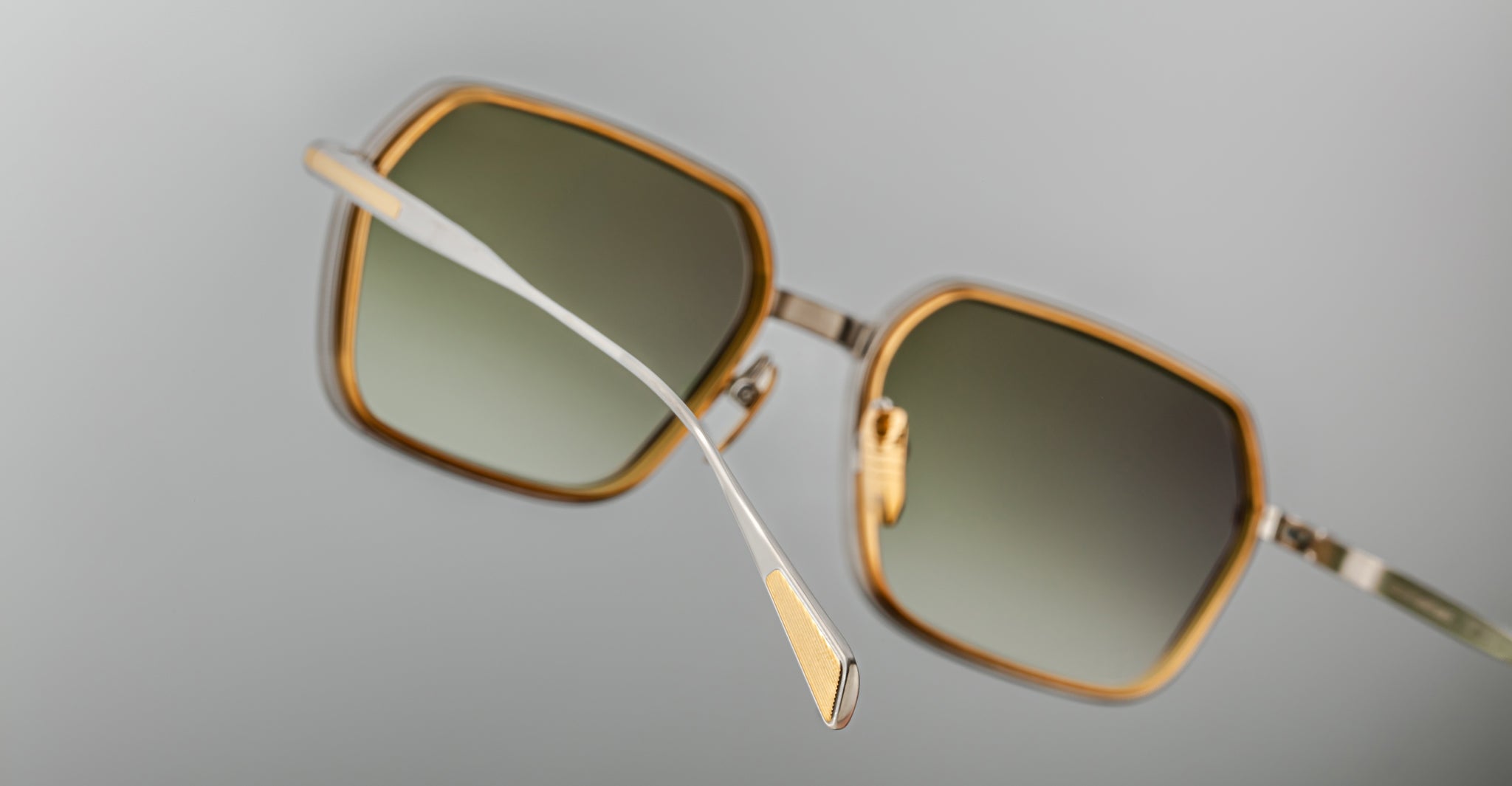 Close-up of Jacques Marie Mage Admiral sunglasses featuring square gold-rimmed frames and green gradient lenses, front view.