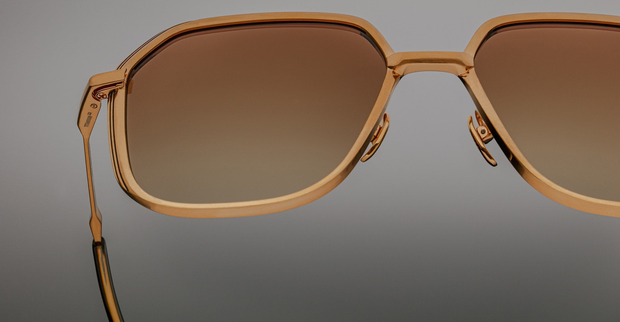 Close-up front view of Jacques Marie Mage Aida sunglasses in gold-tone metal, highlighting the geometric lens shape, sculpted bridge, adjustable nose pads, and brown gradient lenses.