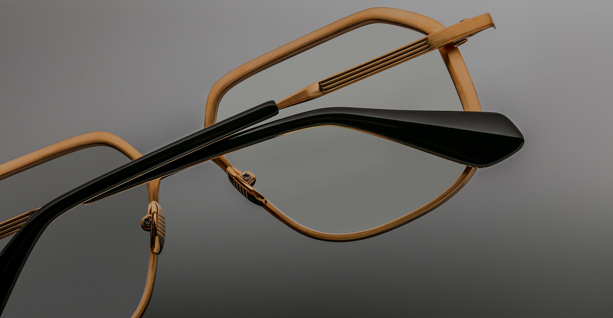 Close-up of Jacques Marie Mage Aida frame in gold-tone metal, highlighting the engraved temple core, adjustable nose pads, and black acetate temple tip detail.