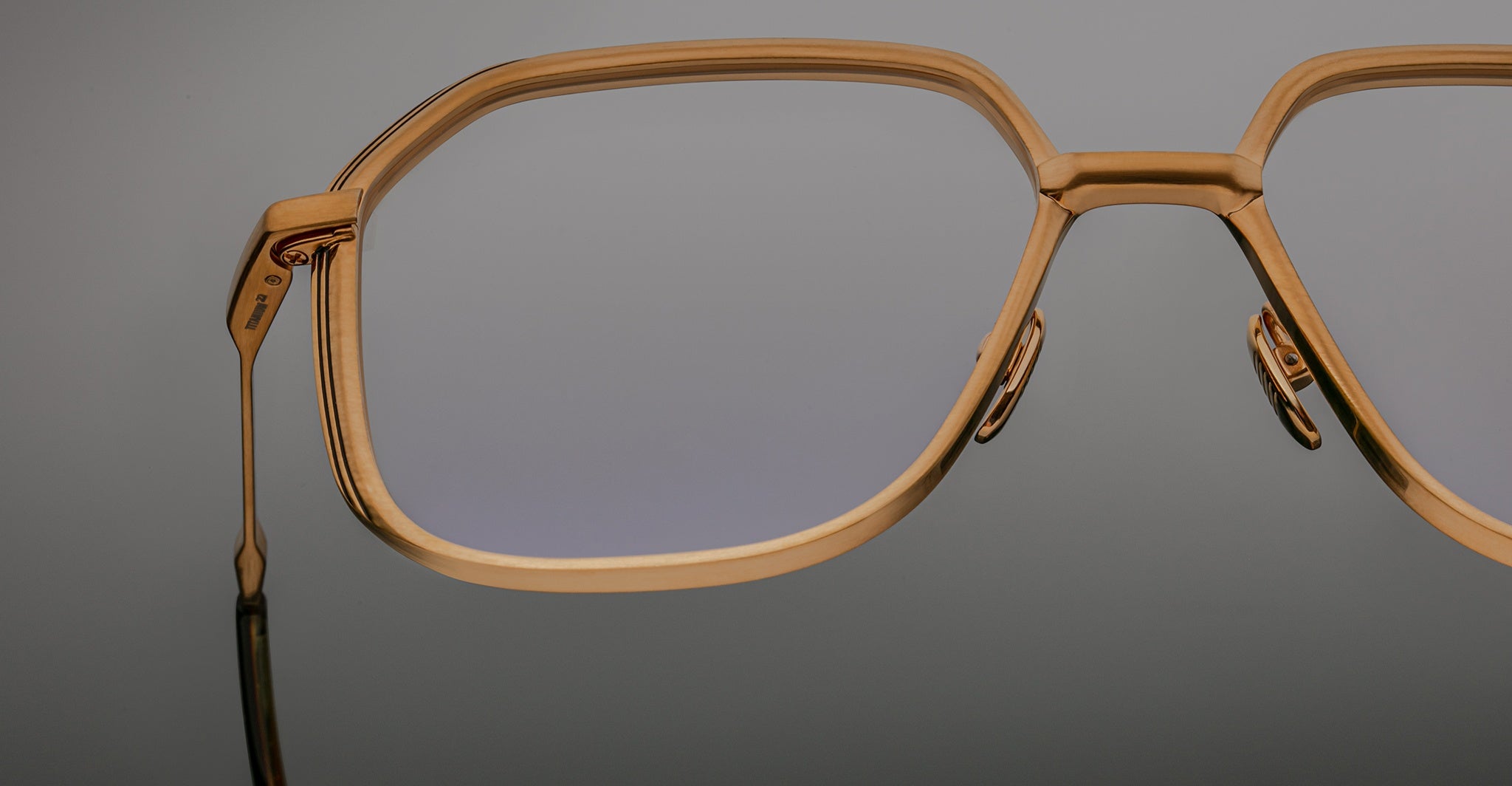 Close-up of Jacques Marie Mage Aida eyeglasses in gold-tone metal, highlighting the geometric lens shape, sculpted bridge, and adjustable nose pads.