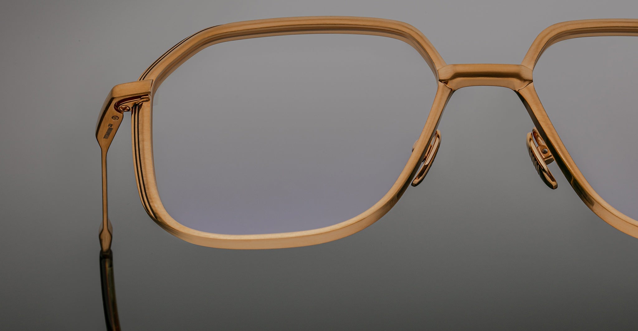 Close-up of Jacques Marie Mage Aida eyeglasses in gold-tone metal, highlighting the geometric lens shape, sculpted bridge, and adjustable nose pads.