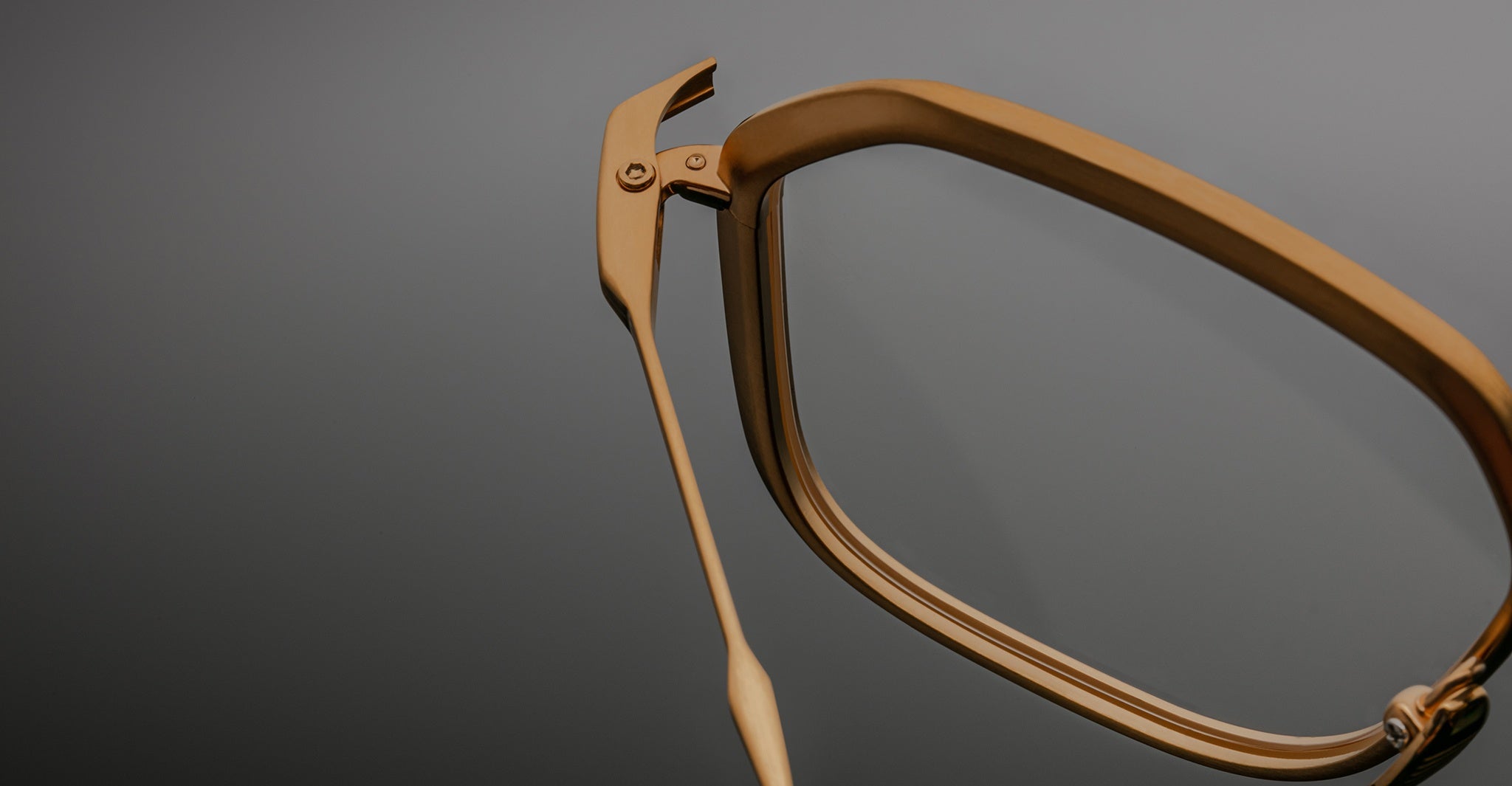Close-up of Jacques Marie Mage Aida frame in gold-tone metal, highlighting the faceted rim construction, hinge detail, and sculpted wire temple.