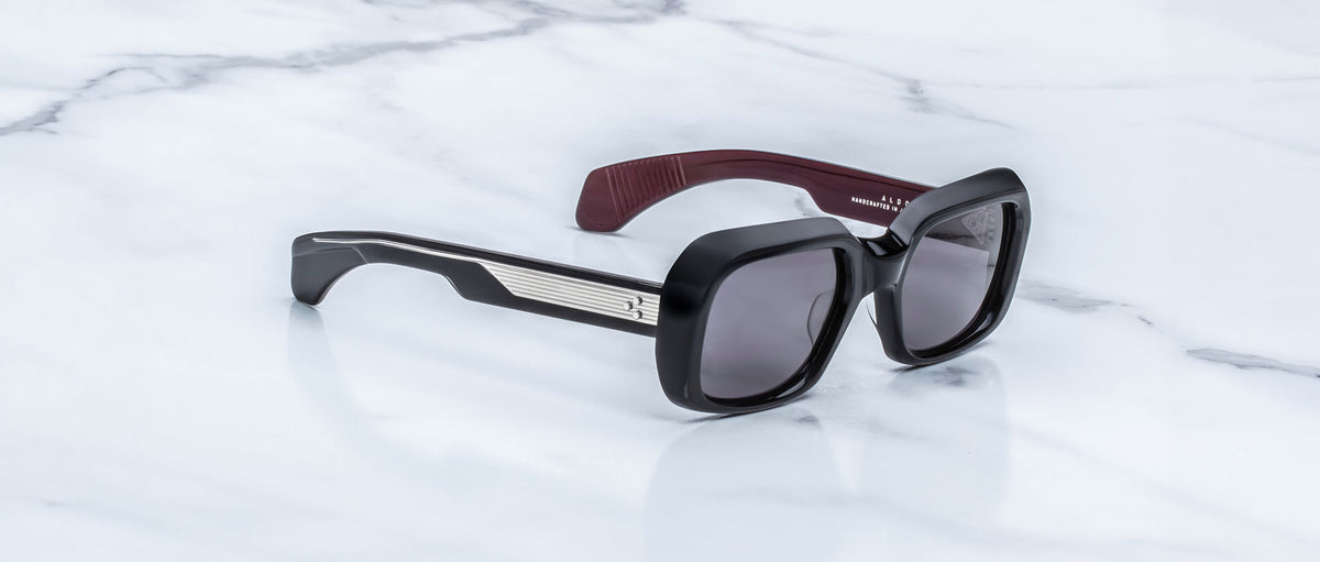Jacques Marie Mage Aldo sunglasses, black rectangular frames with polarized lenses and metallic accents, front view.