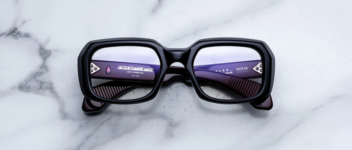 Jacques Marie Mage Aldo black rectangular eyeglasses with digital text reflected in lenses, shown from above.