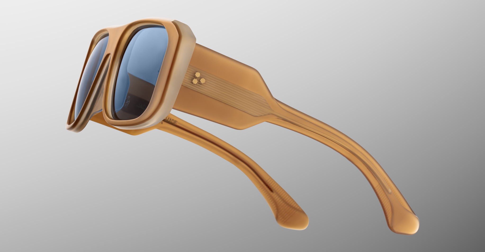 Close-up of Jacques Marie Mage Alfie sunglasses, tan thick geometric frames and blue lenses, viewed from the front.