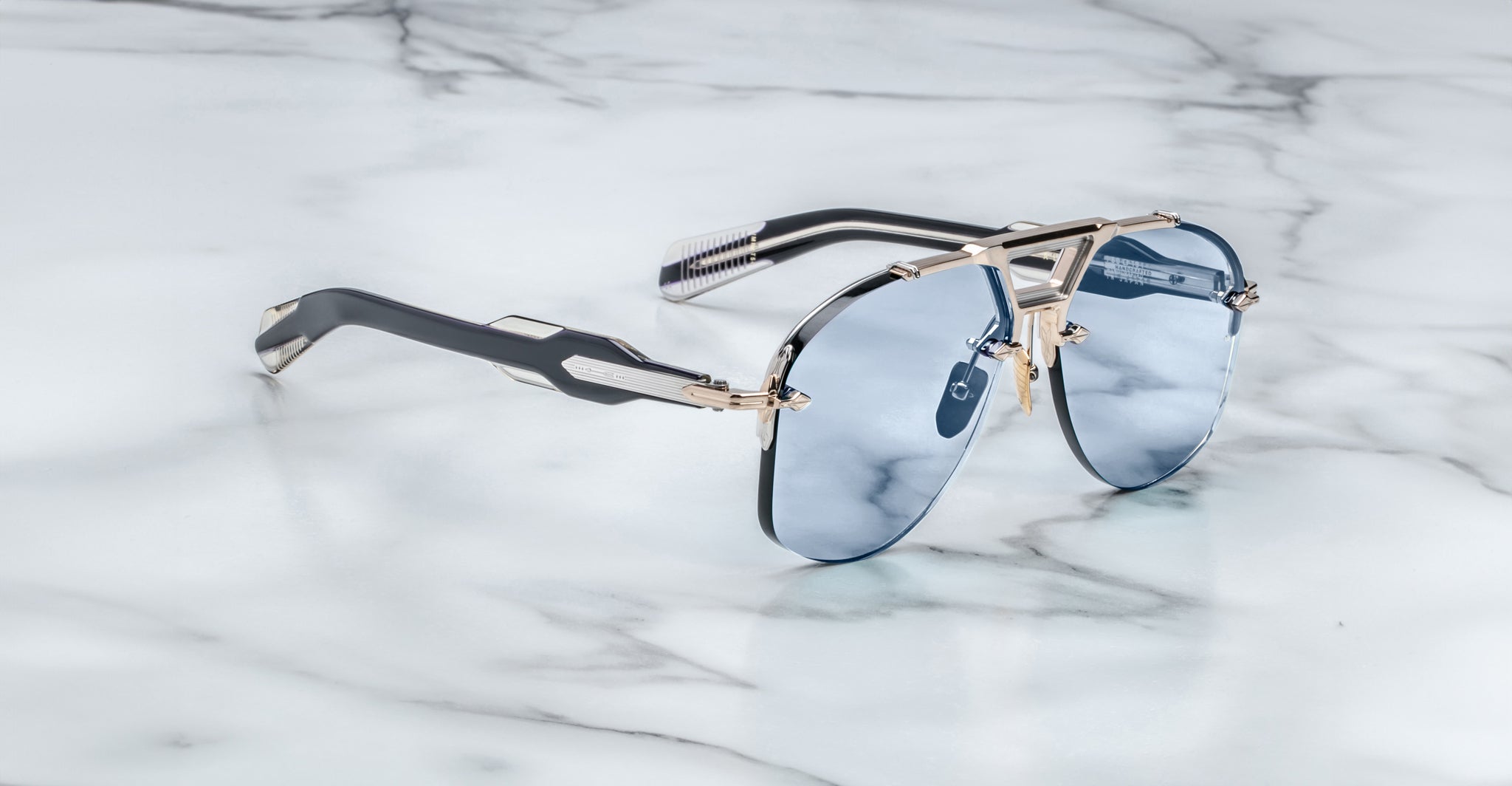 Jacques Marie Mage Alta sunglasses with blue lenses and metallic frames, top-down view.