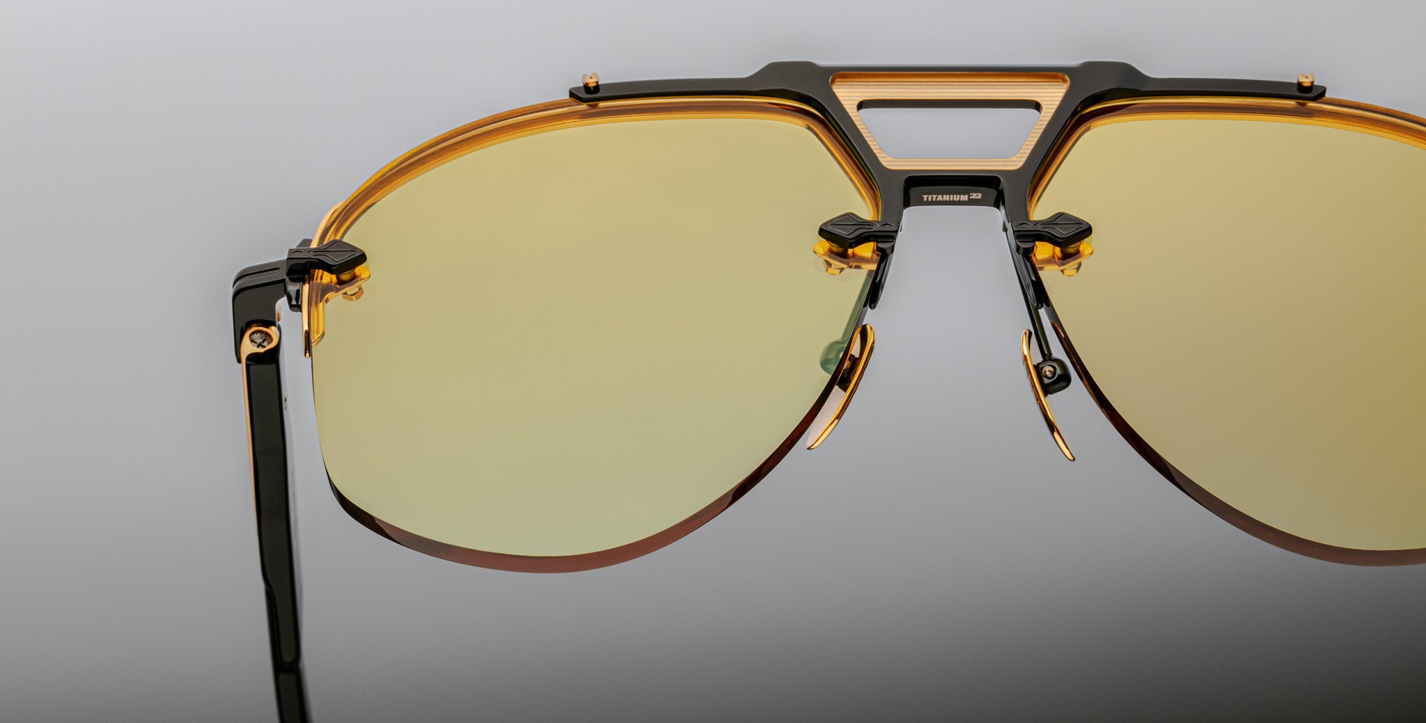 Close-up of Jacques Marie Mage Alta aviator sunglasses with yellow-tinted lenses and black and gold frame, front angle view.