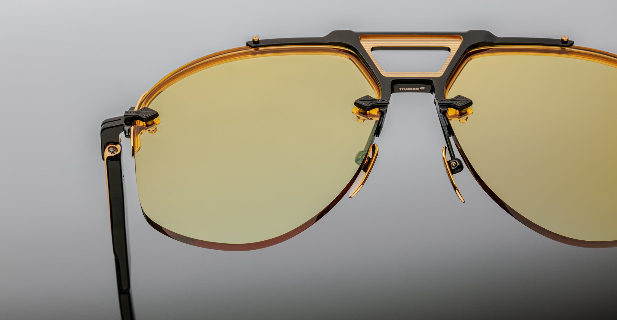 Close-up of Jacques Marie Mage Alta aviator sunglasses with yellow-tinted lenses and black and gold frame, front angle view.