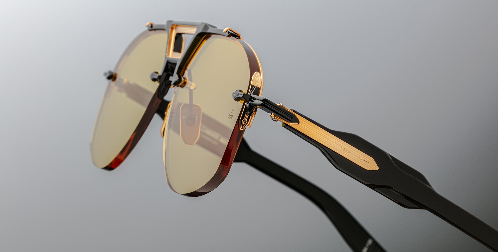 Close-up of Jacques Marie Mage Alta sunglasses featuring gold accents, yellow lenses, and black acetate temples, front angle view.