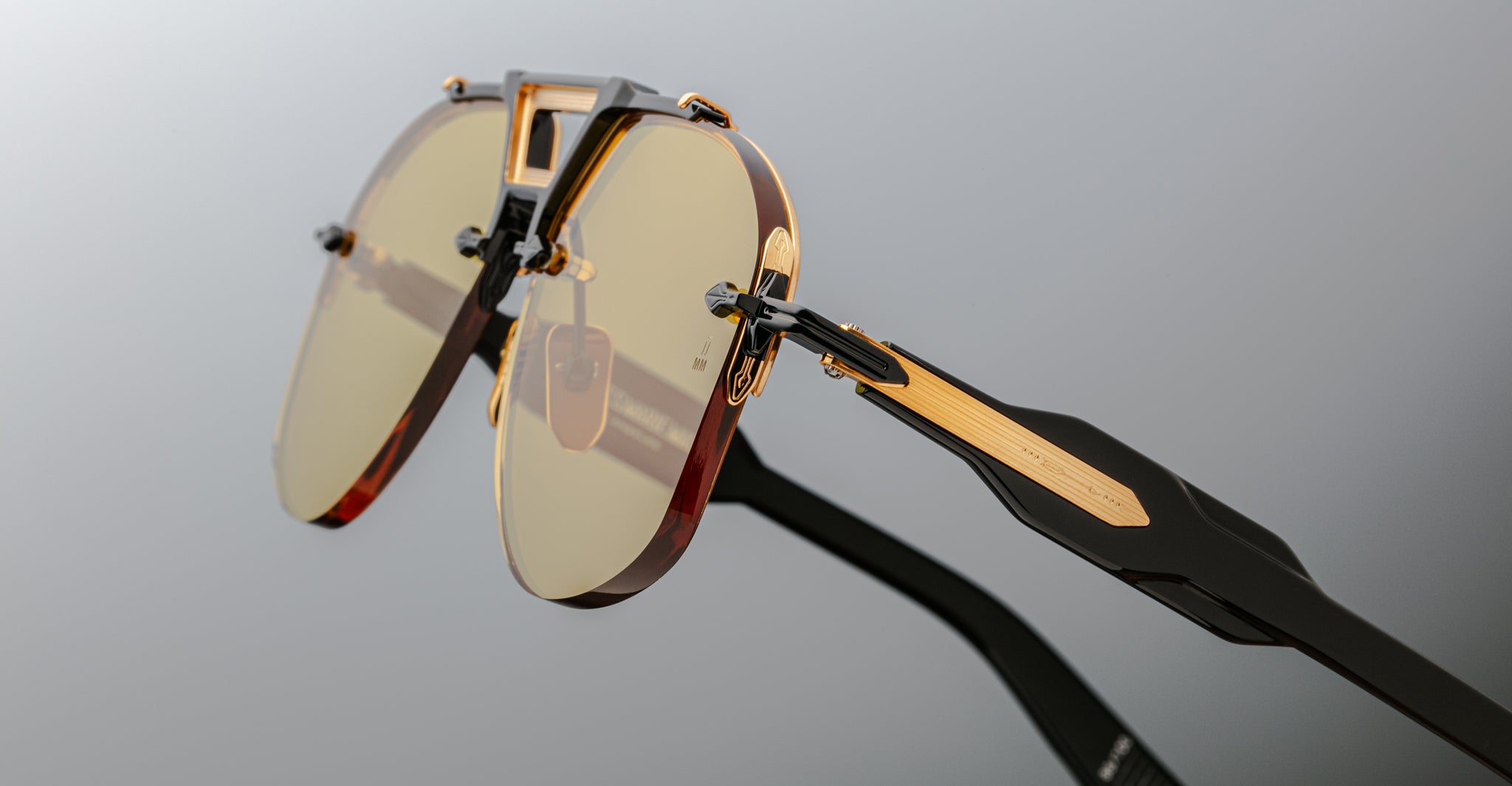 Close-up of Jacques Marie Mage Alta sunglasses featuring gold accents, yellow lenses, and black acetate temples, front angle view.