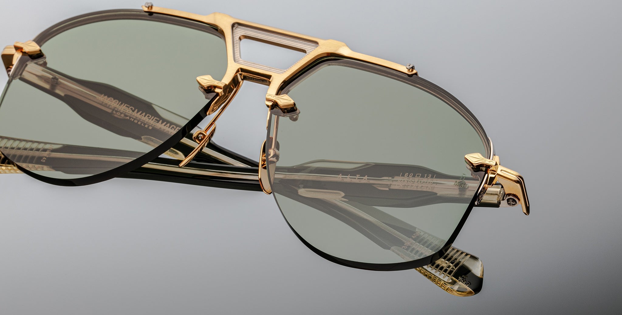 Jacques Marie Mage Alta sunglasses with gold frames and green lenses, shown from above.
