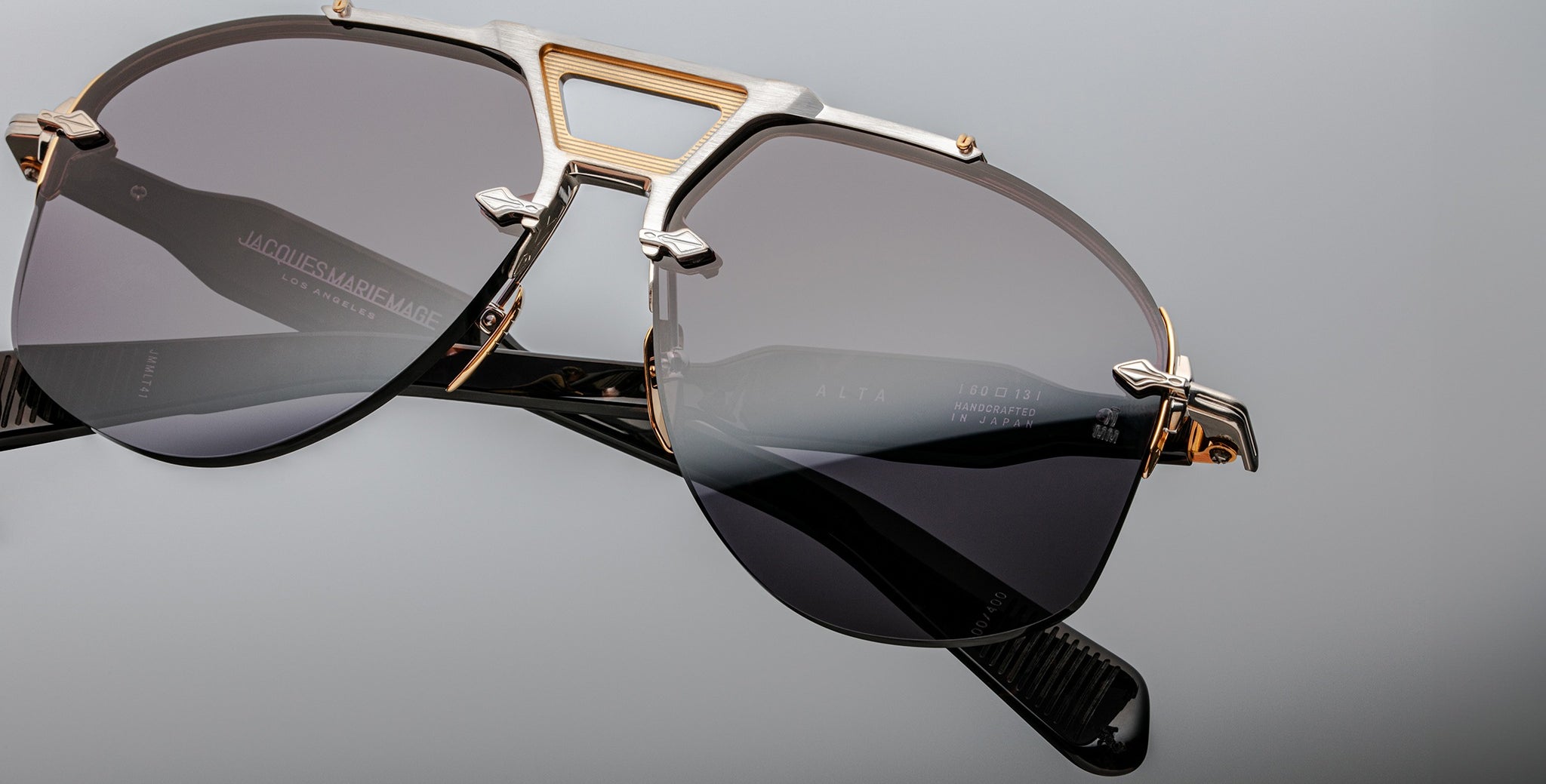 Close-up of Jacques Marie Mage Alta sunglasses, featuring gold and silver accents with dark tinted lenses, viewed from the front.