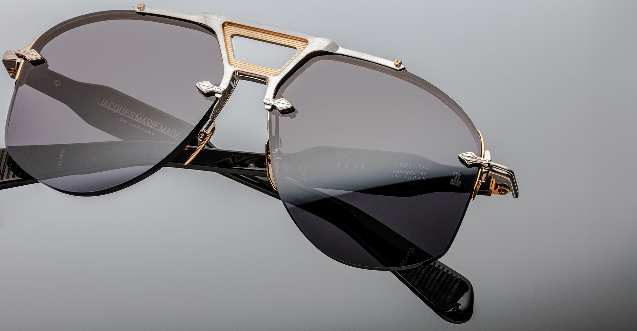 Close-up of Jacques Marie Mage Alta sunglasses, featuring gold and silver accents with dark tinted lenses, viewed from the front.