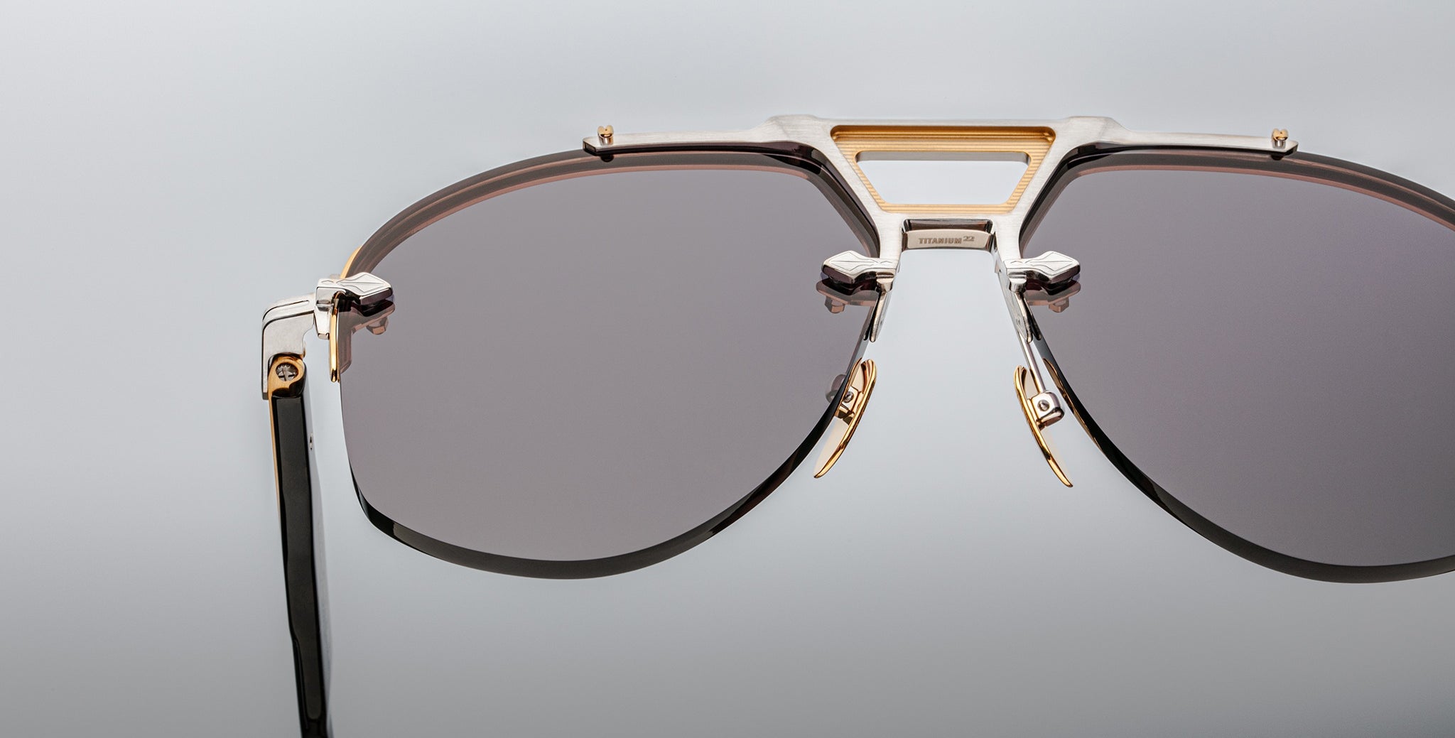 Close-up view of Jacques Marie Mage Alta sunglasses featuring dark lenses, gold accents, and black lightweight arms.