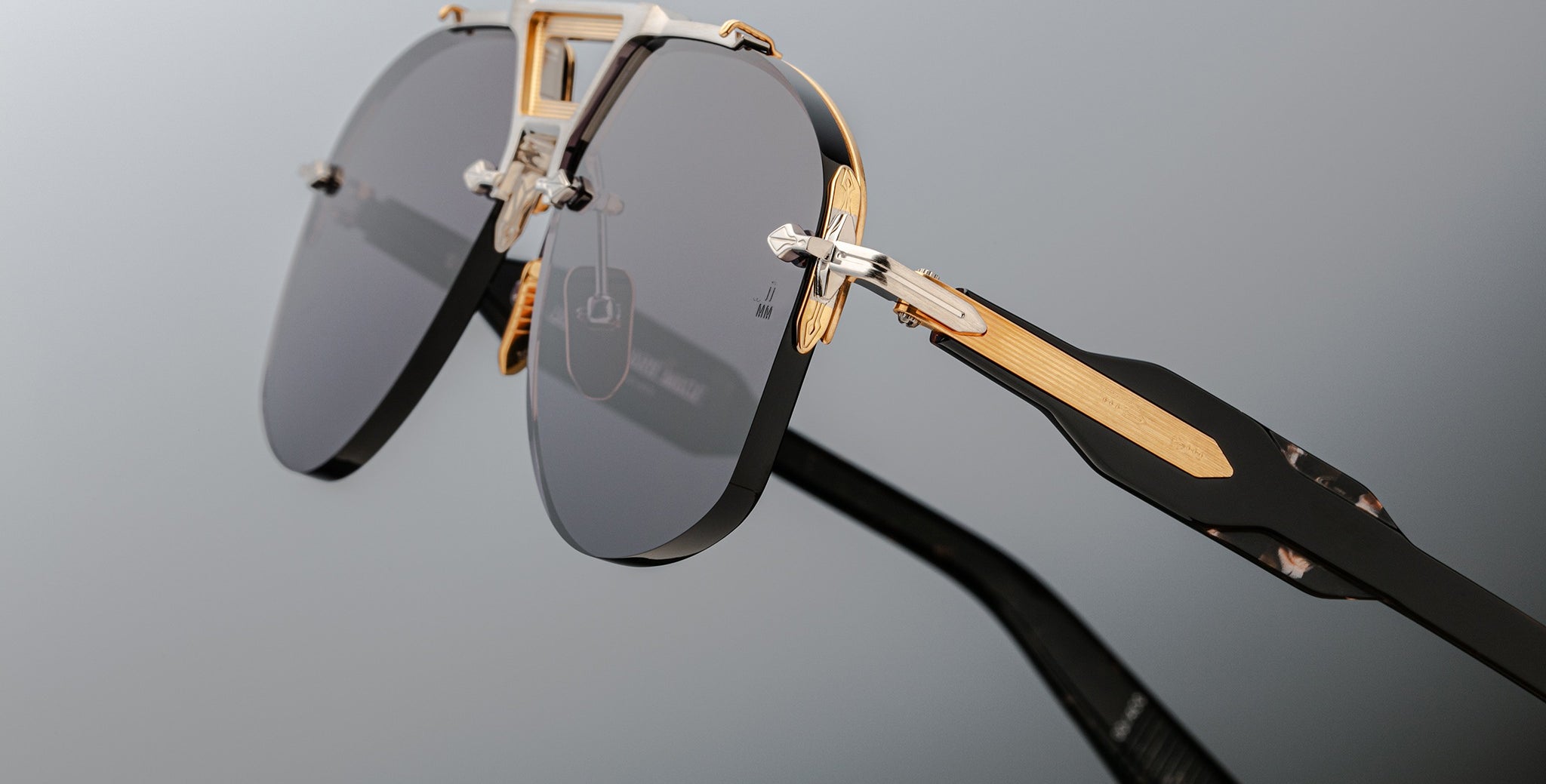 Close-up of Jacques Marie Mage Alta sunglasses with black lenses, gold accents, and geometric temples, front angle view.