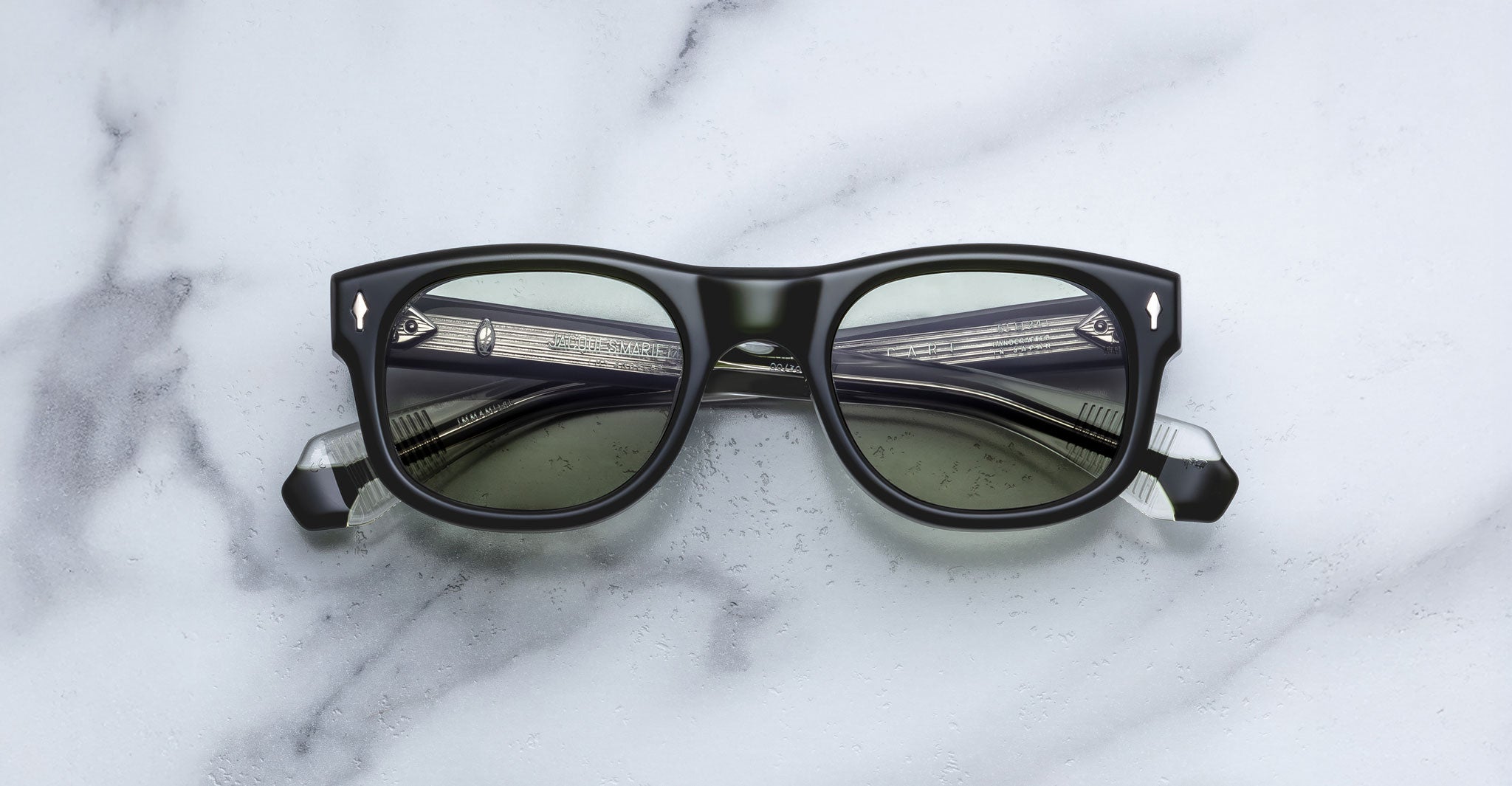 Jacques Marie Mage Amilcar aviator sunglasses with thick black frames and silver accents, shown from above.
