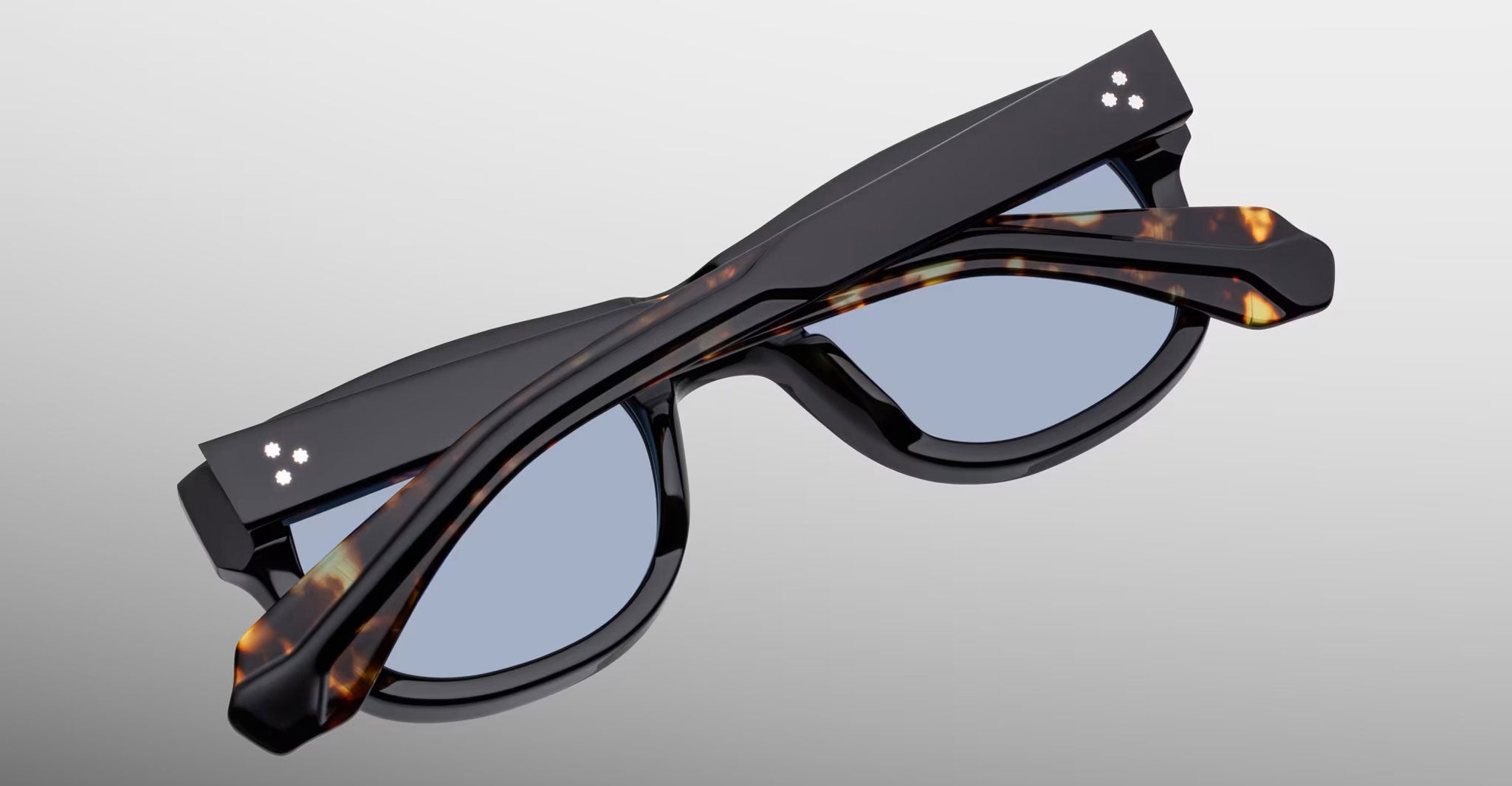 Jacques Marie Mage Amilcar folding sunglasses in black and tortoiseshell, shown side by side, viewed from above.