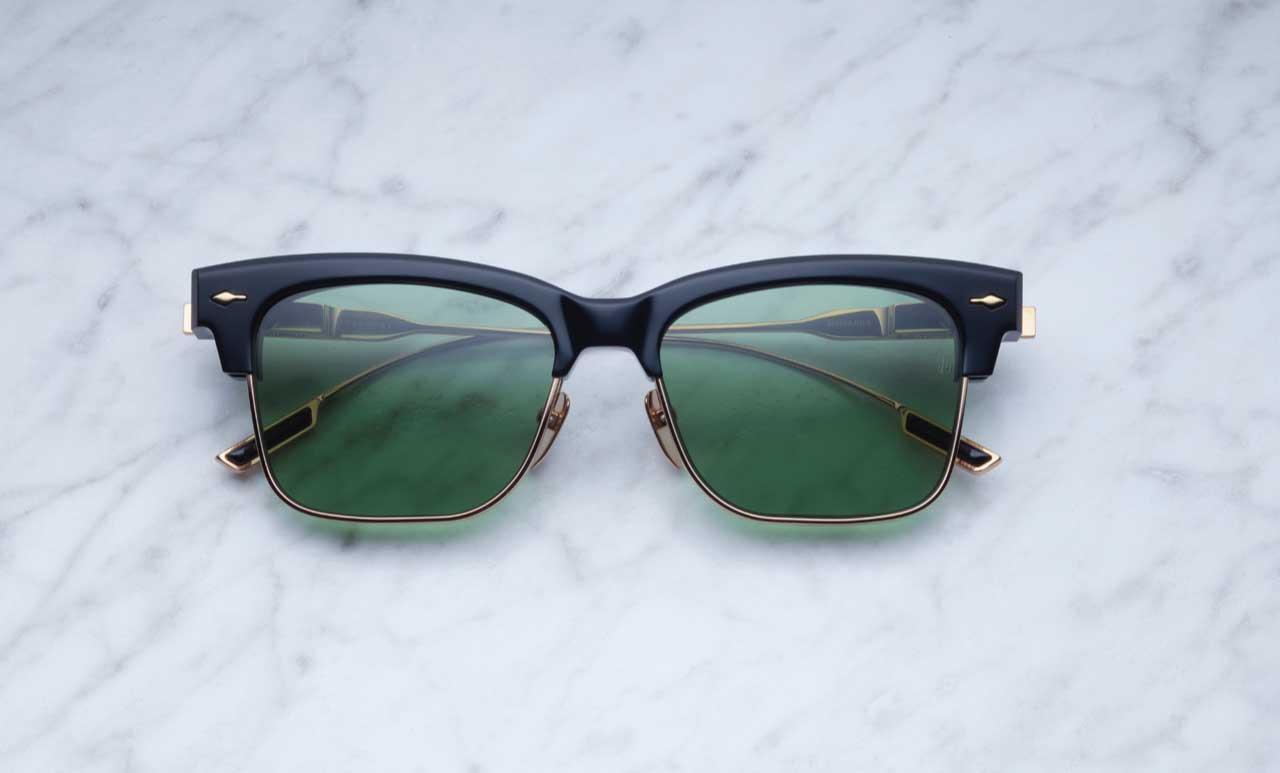 Jacques Marie Mage Apache sunglasses, black and gold frame with green lenses, viewed from above.