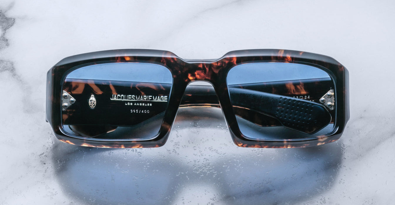 Front view of Jacques Marie Mage Apollo in Agar featuring a bold rectangular frame in dark tortoiseshell acetate, thick sculpted rims, blue-tinted lenses, and hinge hardware visible through the lens.