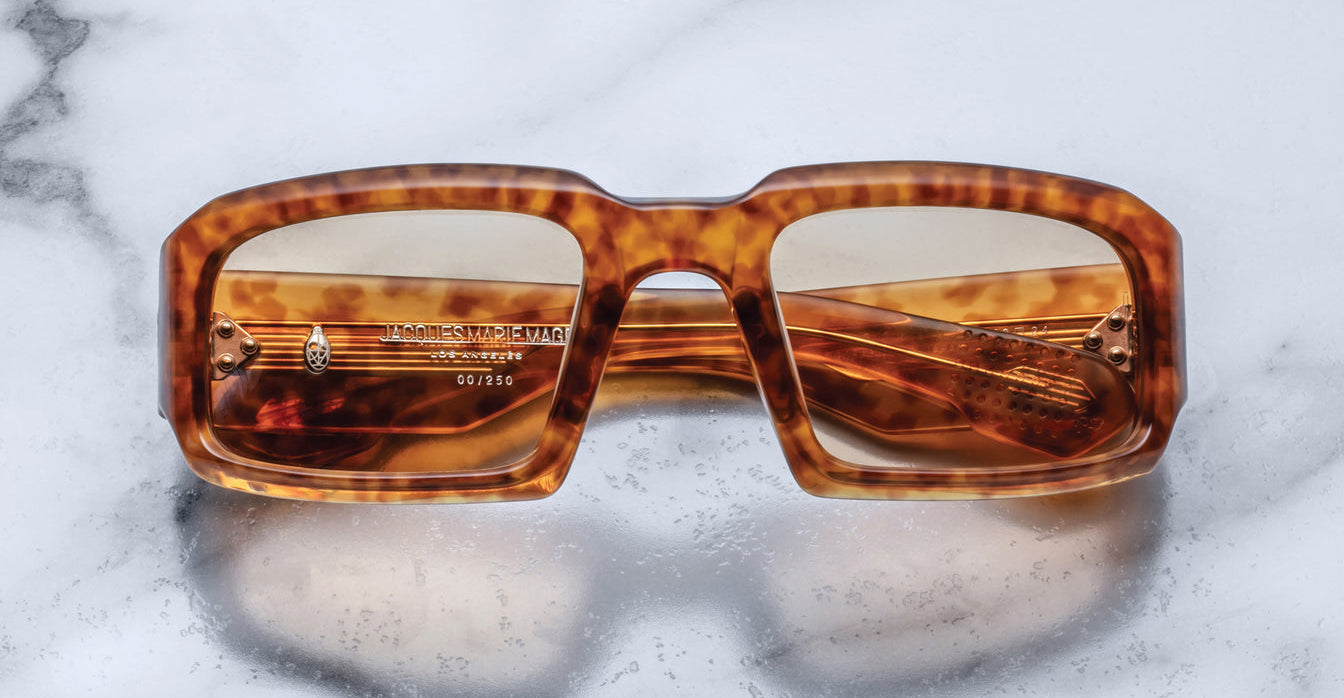Front view of Jacques Marie Mage Apollo in Camel featuring a bold rectangular frame in warm tortoiseshell acetate, thick sculpted rims, amber-tinted lenses, and metal hinges visible through the lens.