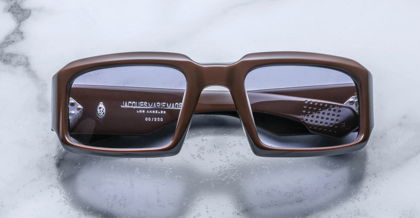 Front view of Jacques Marie Mage Apollo in Chocolate featuring a bold rectangular frame in rich brown acetate, thick sculpted rims, subtle tinted lenses, and signature metal hinge details visible through the lens.