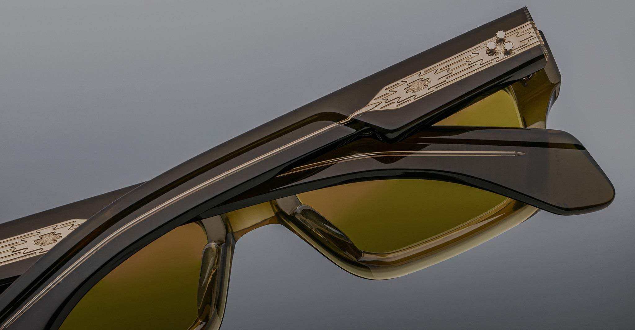 A close-up of the temples on two Jacques Marie Mage Ashcroft eyeglasses, featuring intricate gold detailing and patterns on the arms, set against a neutral background.