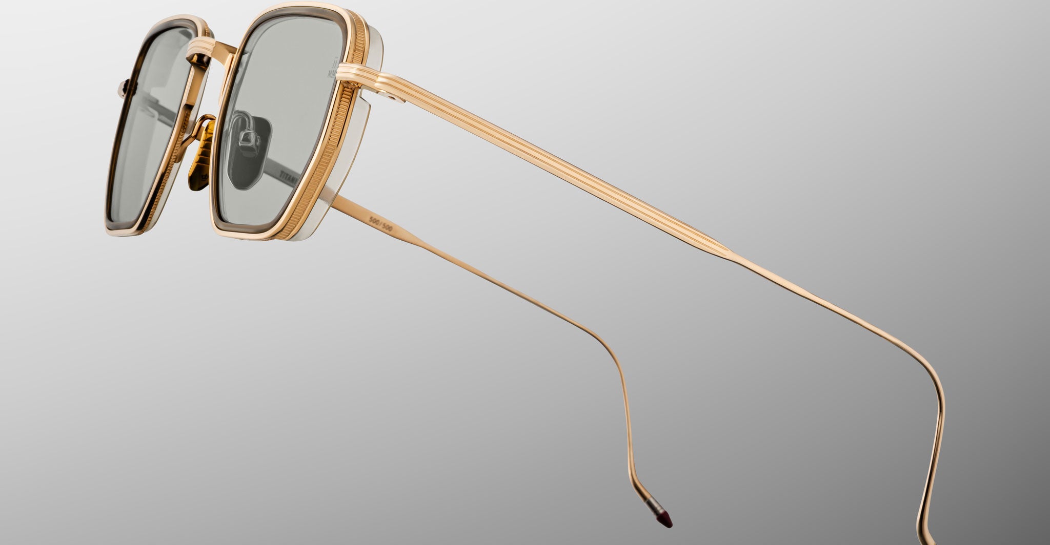 Close-up of Jacques Marie Mage Atkins sunglasses, featuring a gold frame, rectangular dark lenses, and a modern style.