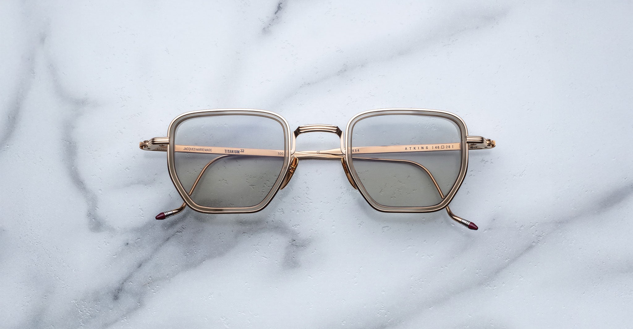Jacques Marie Mage Atkins gold square eyeglasses with clear blue light lenses, top-down view.