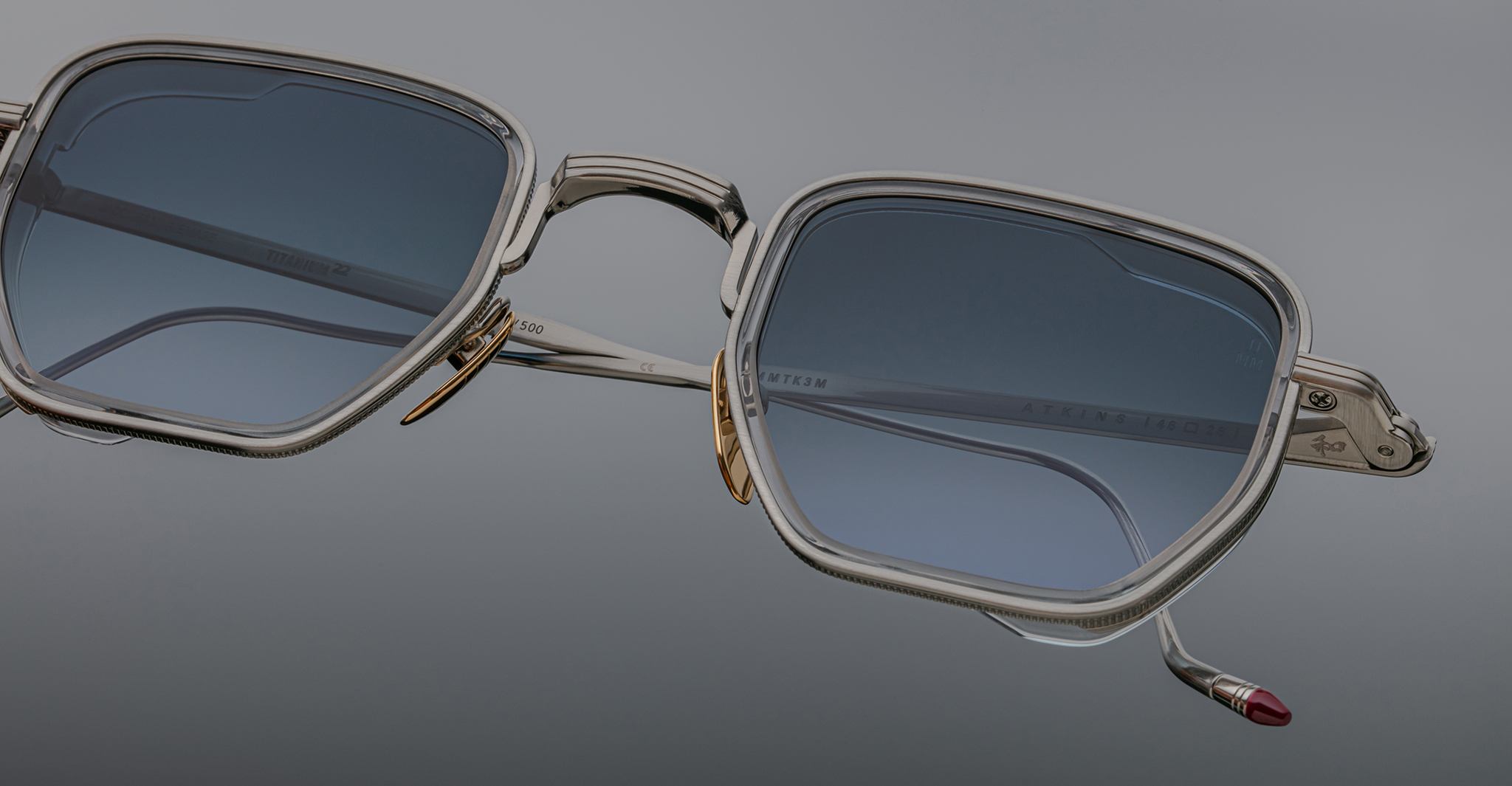 Close-up of Jacques Marie Mage Atkins sunglasses with silver metal frames and blue-tinted lenses, viewed from the front.
