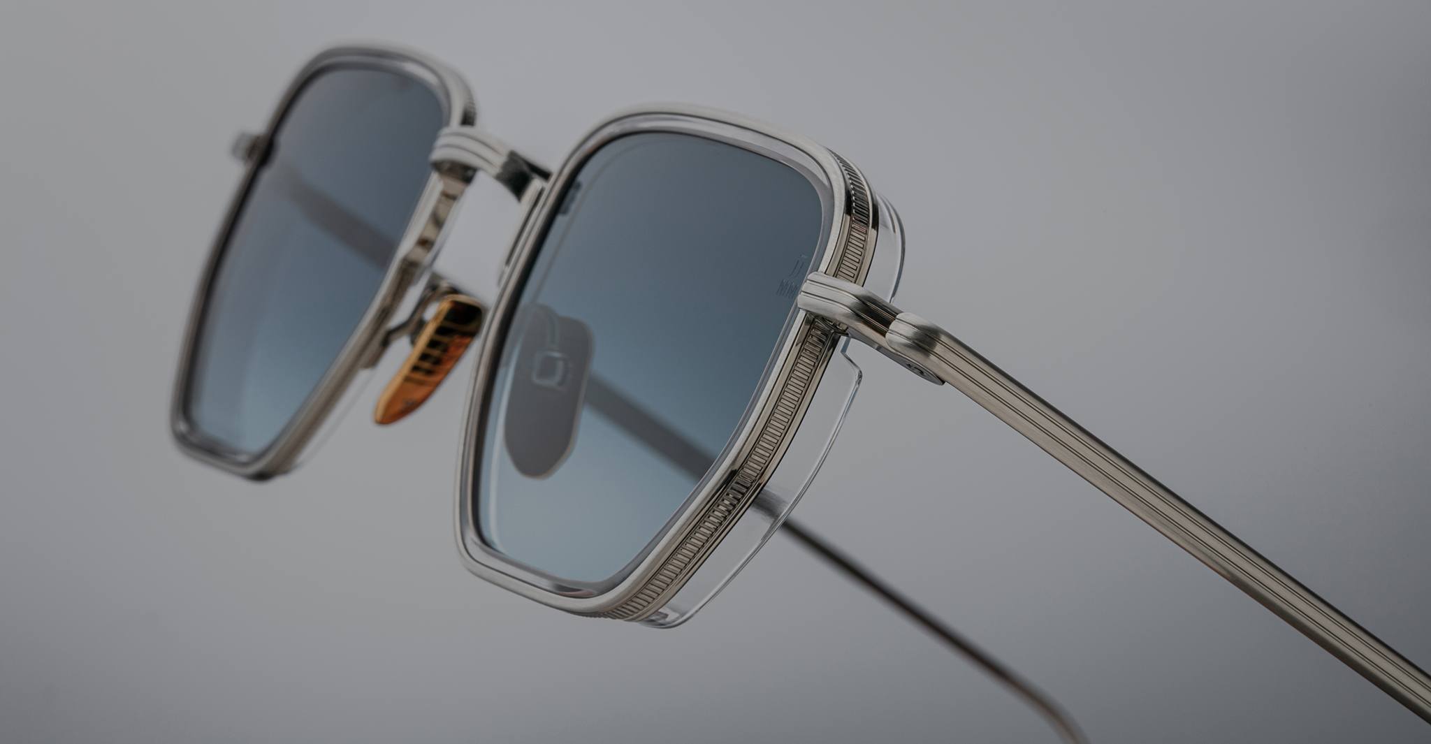 Close-up of Jacques Marie Mage Atkins sunglasses, silver frame with blue lenses, viewed from the front.
