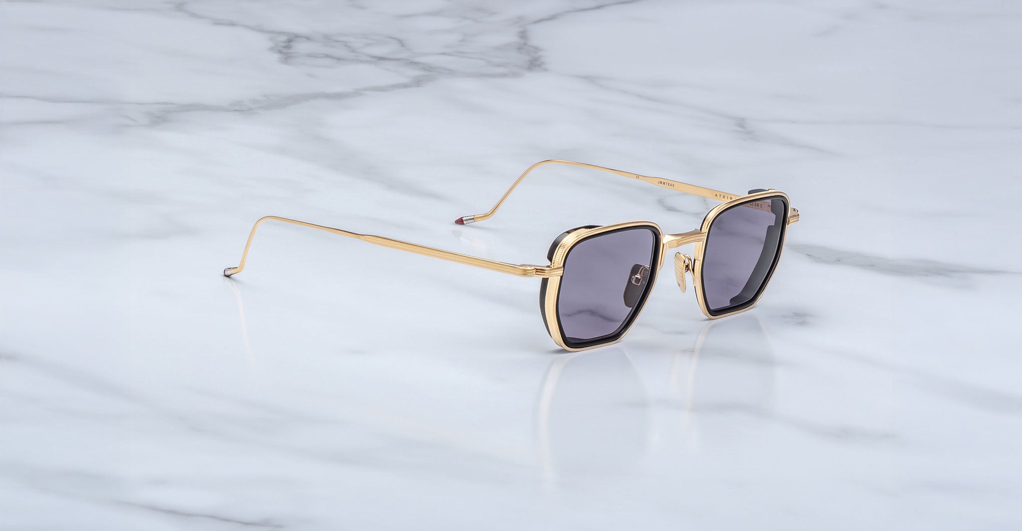 Jacques Marie Mage Atkins square sunglasses with gold frames and dark lenses, top view.