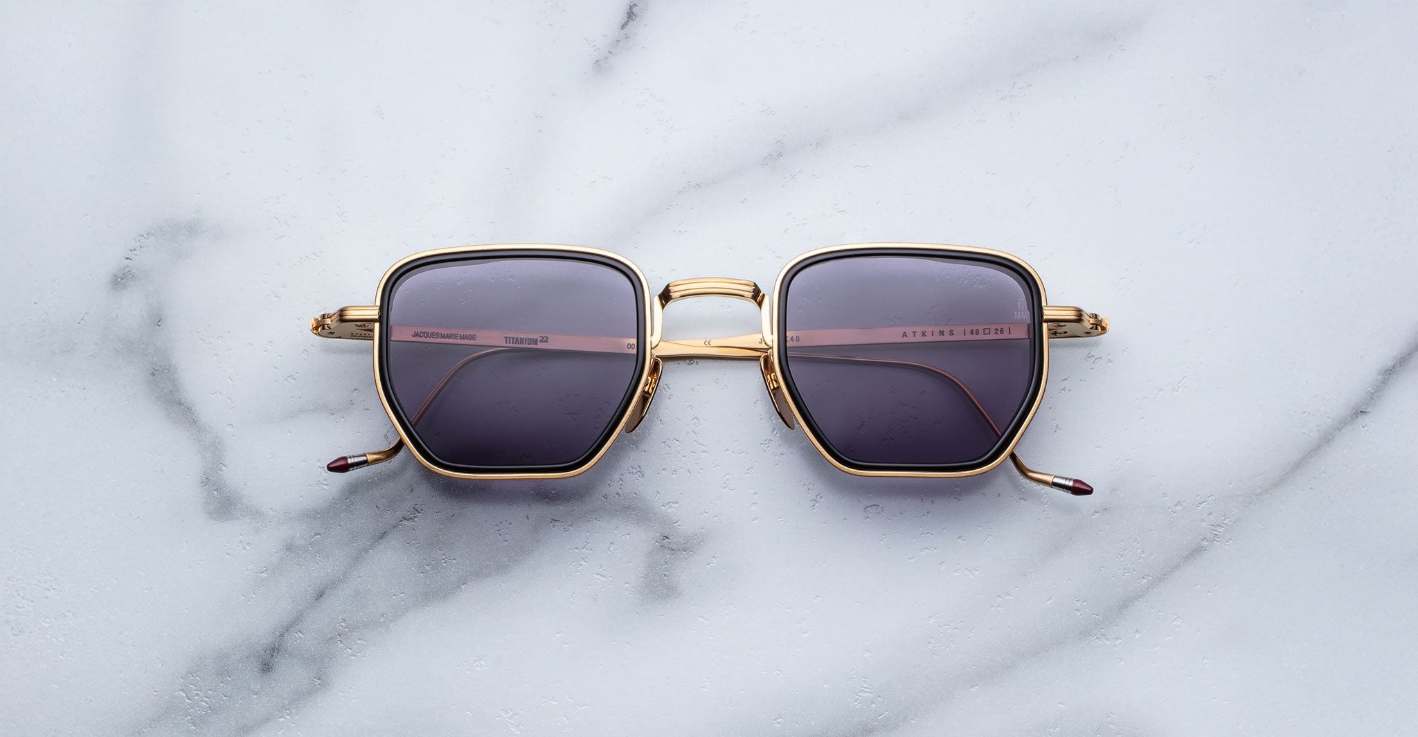 Jacques Marie Mage Atkins sunglasses feature gold frames and dark lenses, shown from above for a clear view of the product design.