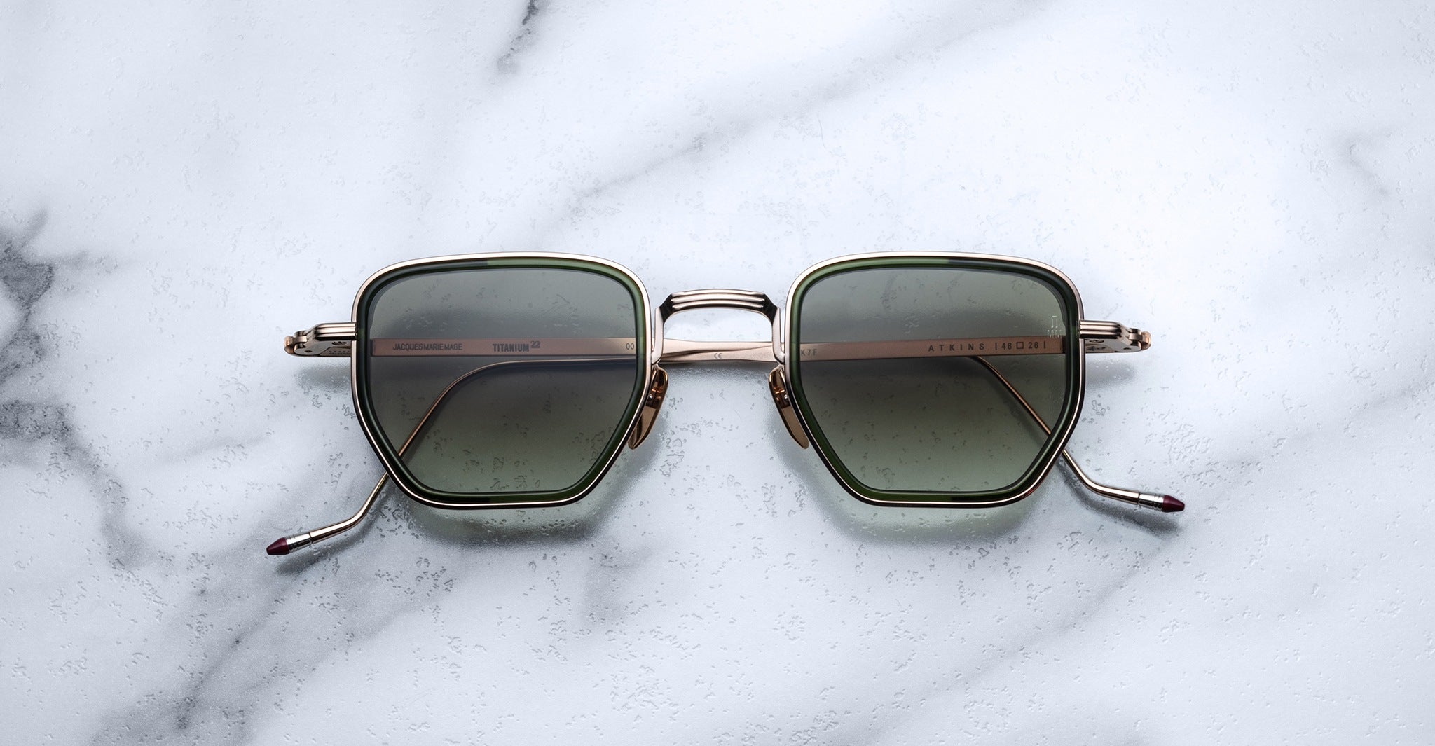 Jacques Marie Mage Atkins square sunglasses with gold rims and UV-protective green lenses, top view.