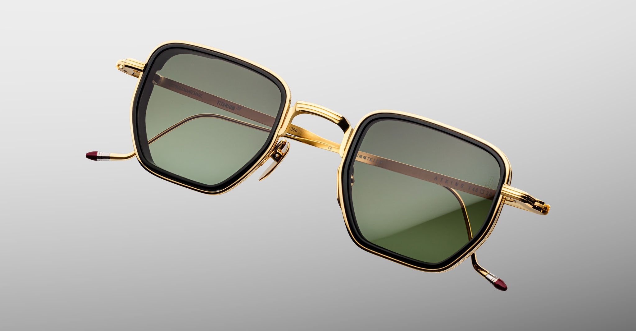 Jacques Marie Mage Atkins square sunglasses with gold frames and green-tinted UV lenses, shown from the front.