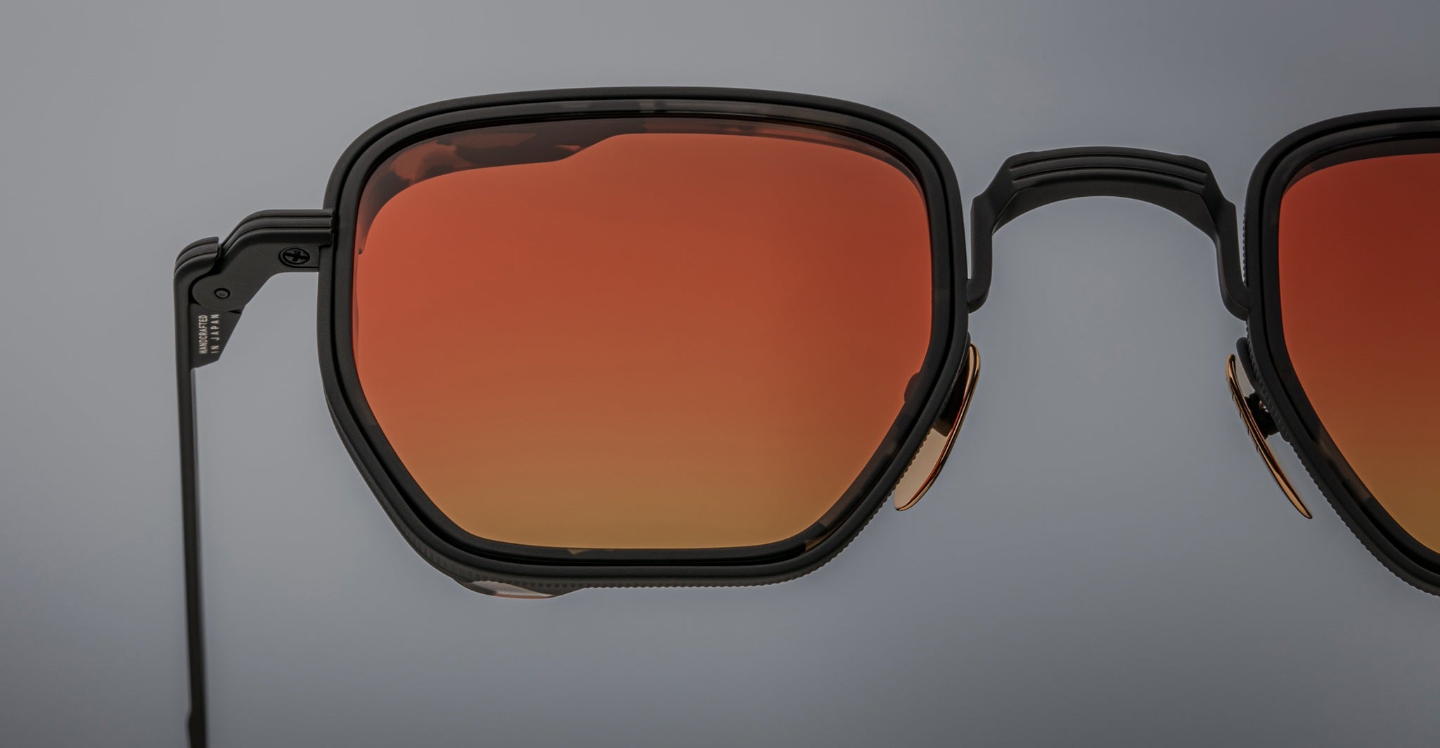 Close-up of Jacques Marie Mage Atkins geometric black sunglasses with orange-tinted lenses, shown from the front angle.