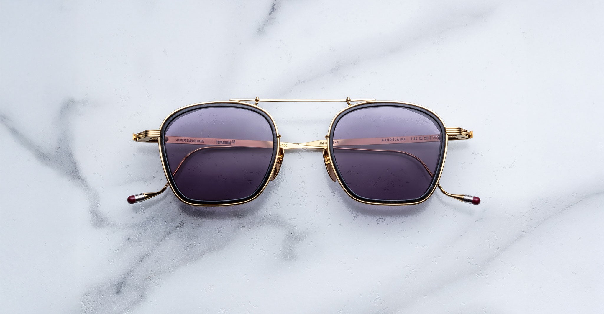 Jacques Marie Mage Baudelaire 2 gold square sunglasses with dark lenses, top-down view.