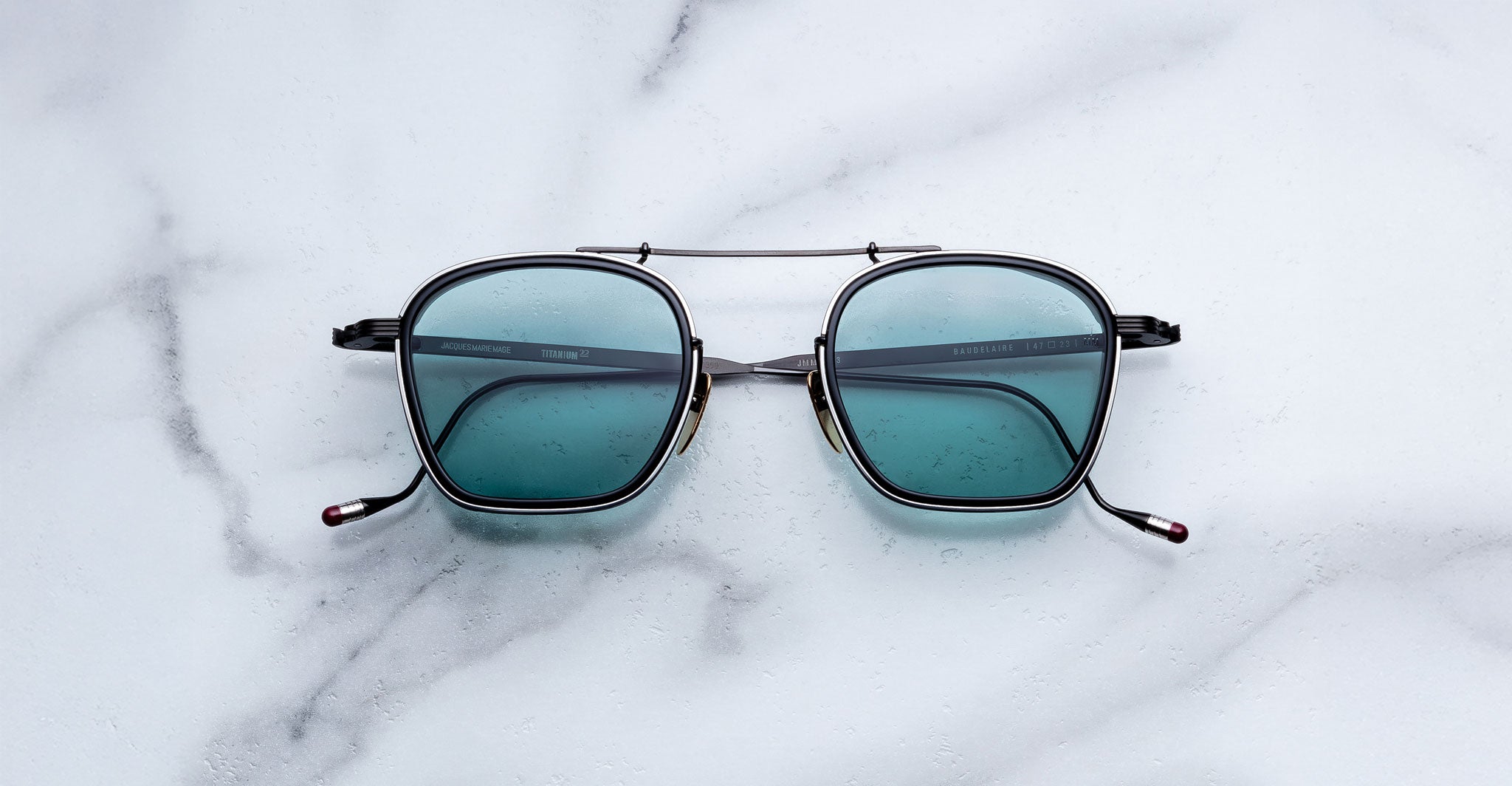 Jacques Marie Mage Baudelaire 2 sunglasses with black frames and blue lenses, top view.