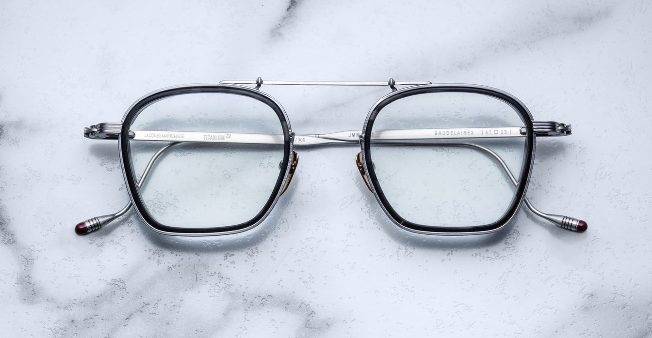 Jacques Marie Mage Baudelaire 2 square metal eyeglasses, prescription type, shown from above on a flat surface.