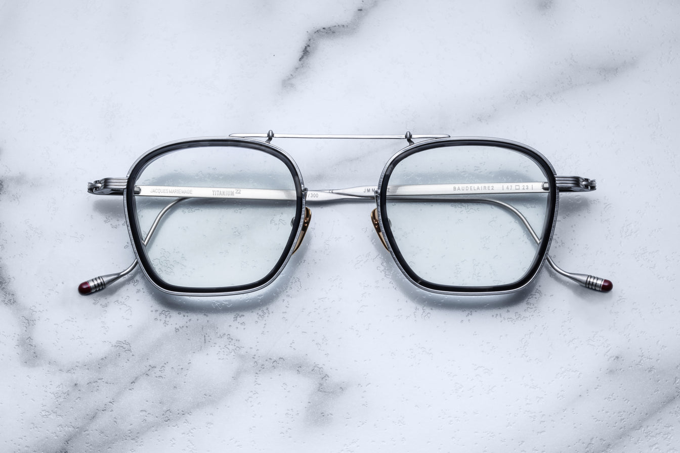 Jacques Marie Mage Baudelaire 2 square metal eyeglasses, prescription type, shown from above on a flat surface.
