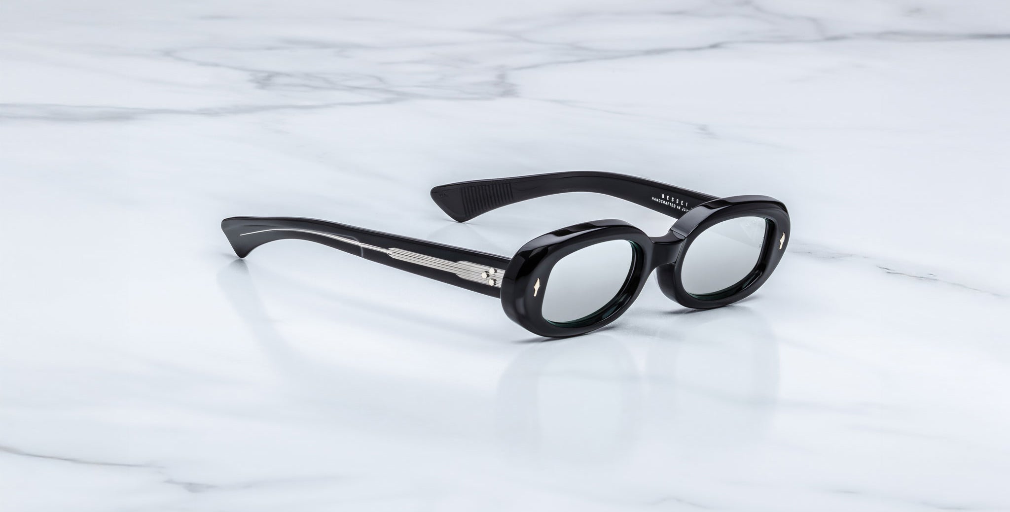 Jacques Marie Mage Besset black oval sunglasses with thick frames and silver accents, top view.