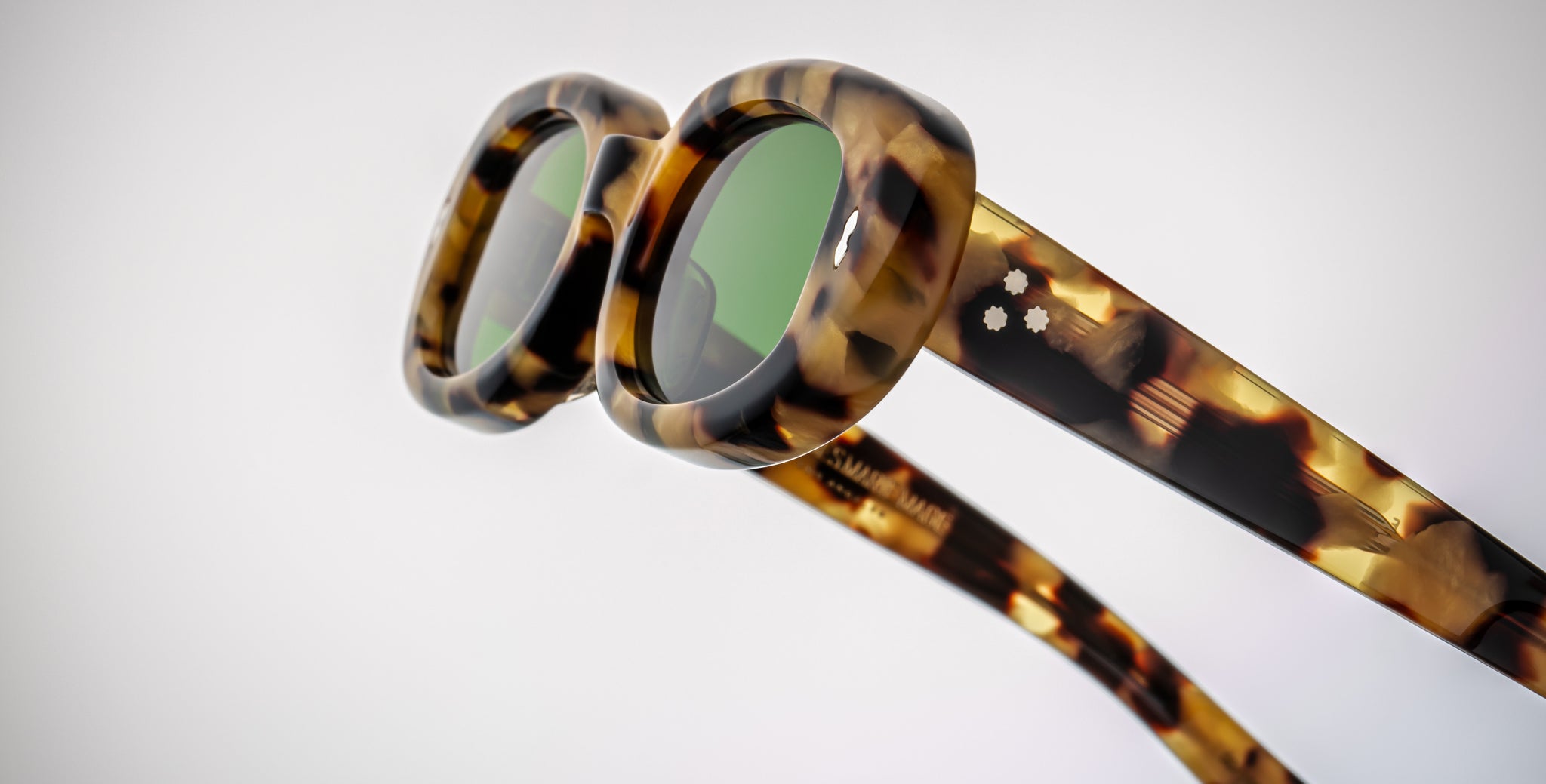 Close-up of Jacques Marie Mage Besset sunglasses, tortoiseshell frame, green UV-protection lenses, front facing.