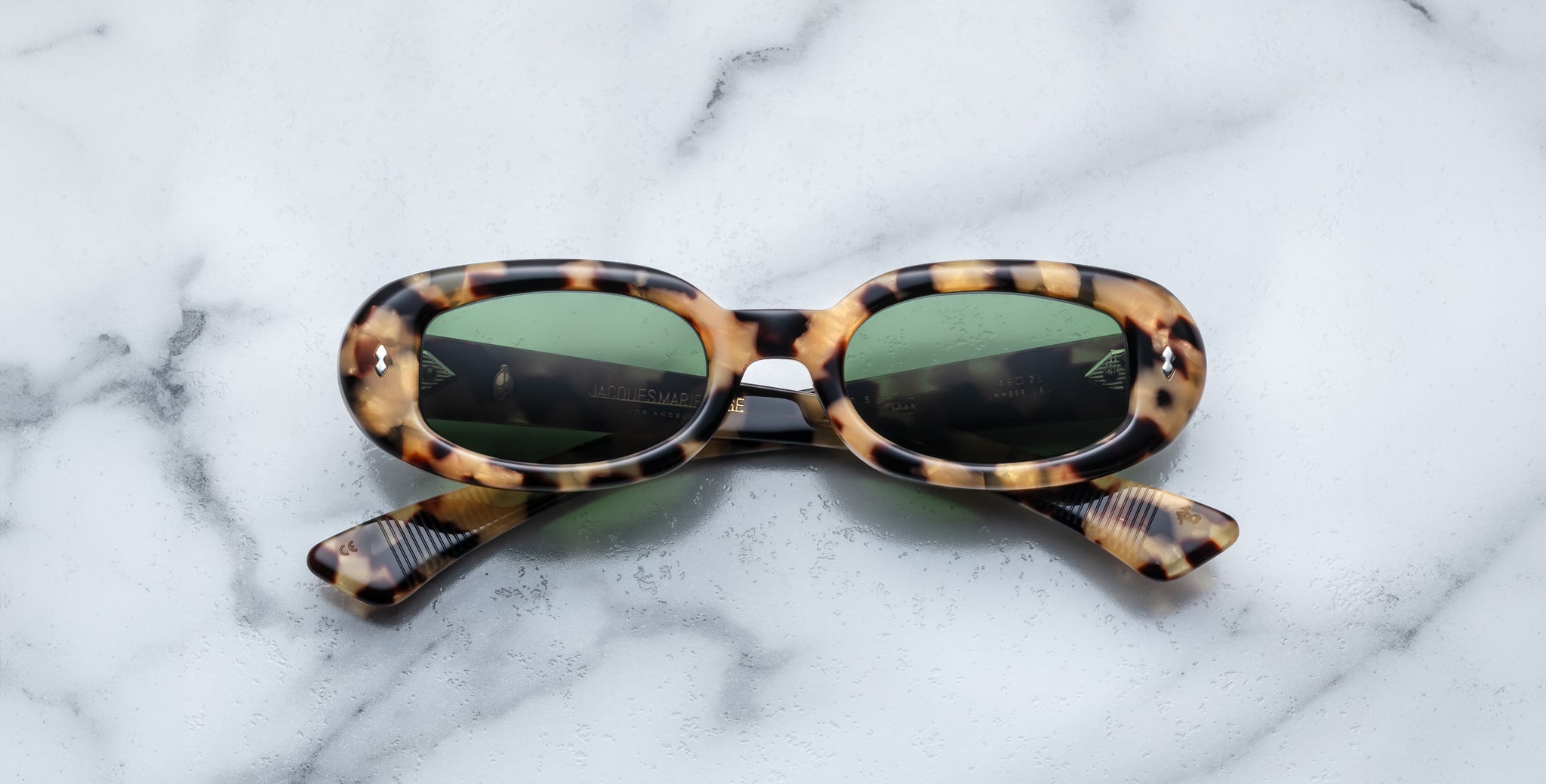 Jacques Marie Mage Besset tortoiseshell oval sunglasses with green lenses, seen from above.