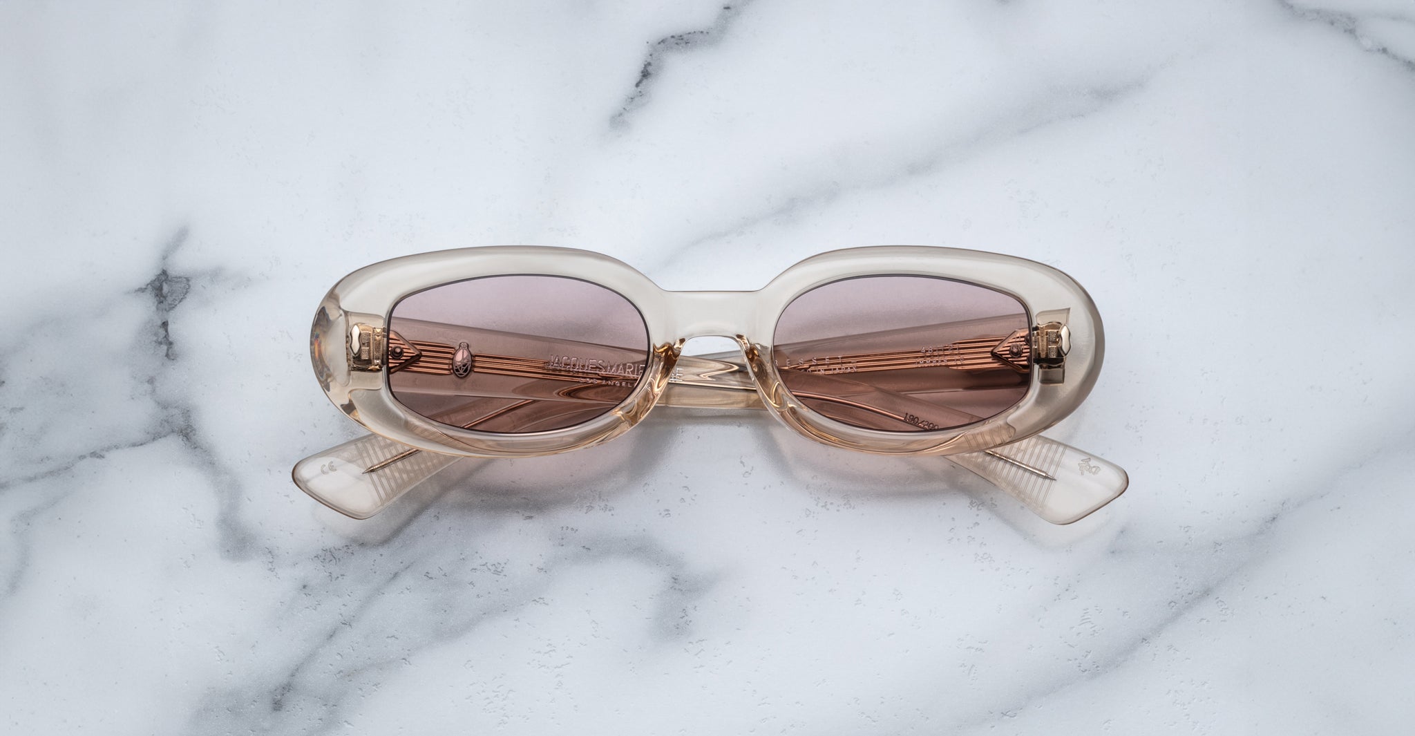 Jacques Marie Mage Besset beige oval sunglasses with brown UV-protective lenses shown from above.