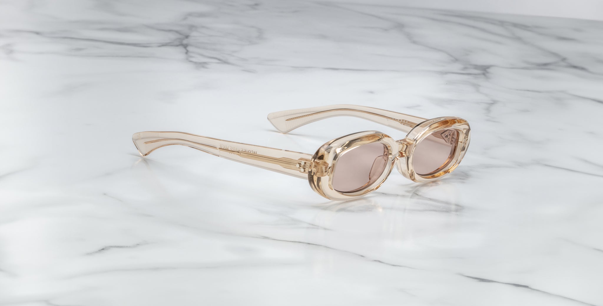 Jacques Marie Mage Besset sunglasses with clear frames and brown lenses, top view.